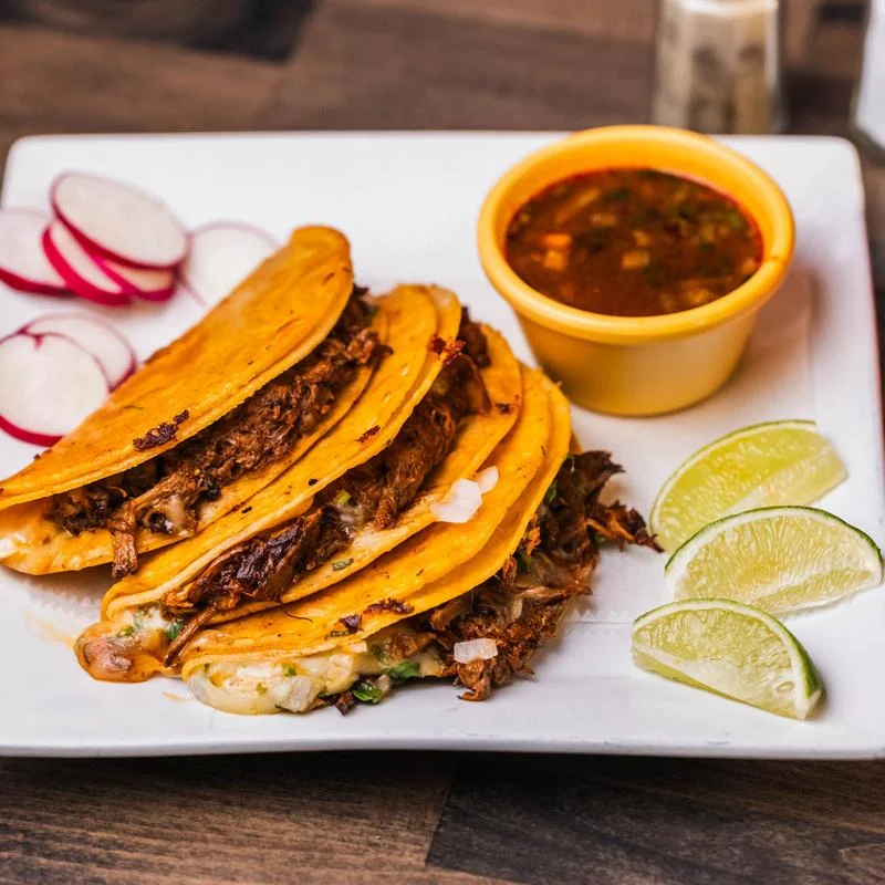 Plate of tacos with beef, lime wedges, and radish slices at La Patrona Restaurant, Mott Haven.