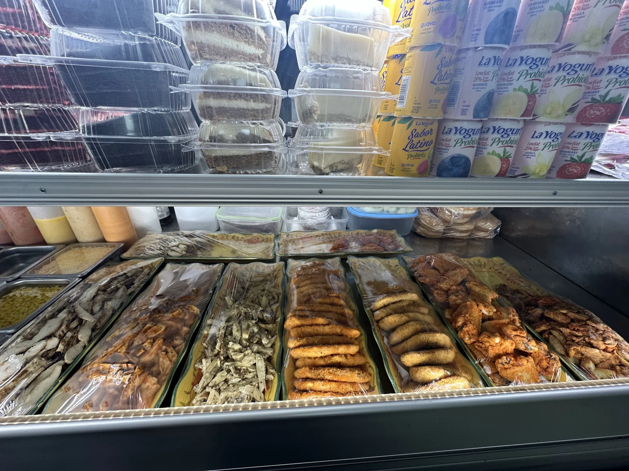 Assorted packaged food items including fries, chicken, and yogurt at Fordham Deli, Fordham, Bronx NYC.