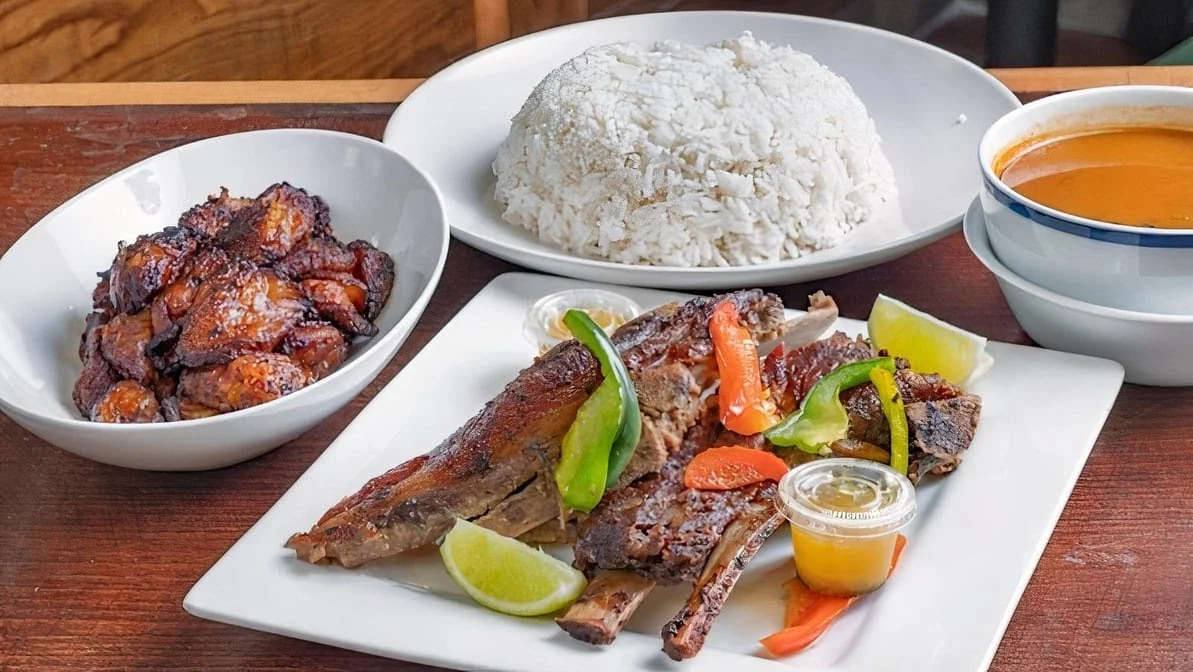 Ribs, white rice, and plantains on plates at Dominicana Pollo Sabroso, Highbridge.
