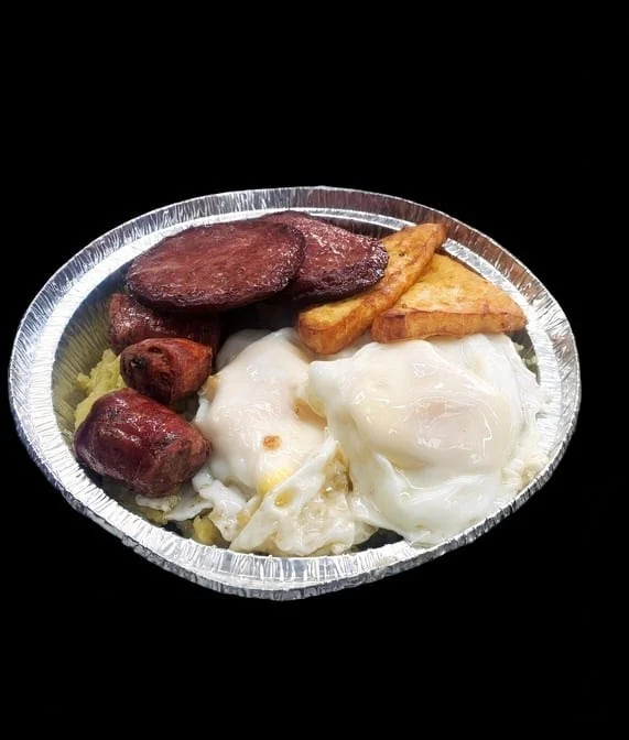 Tin foil tray with cooked eggs, sausage, and fried items at Antojitos del Mangu, Kingsbridge.