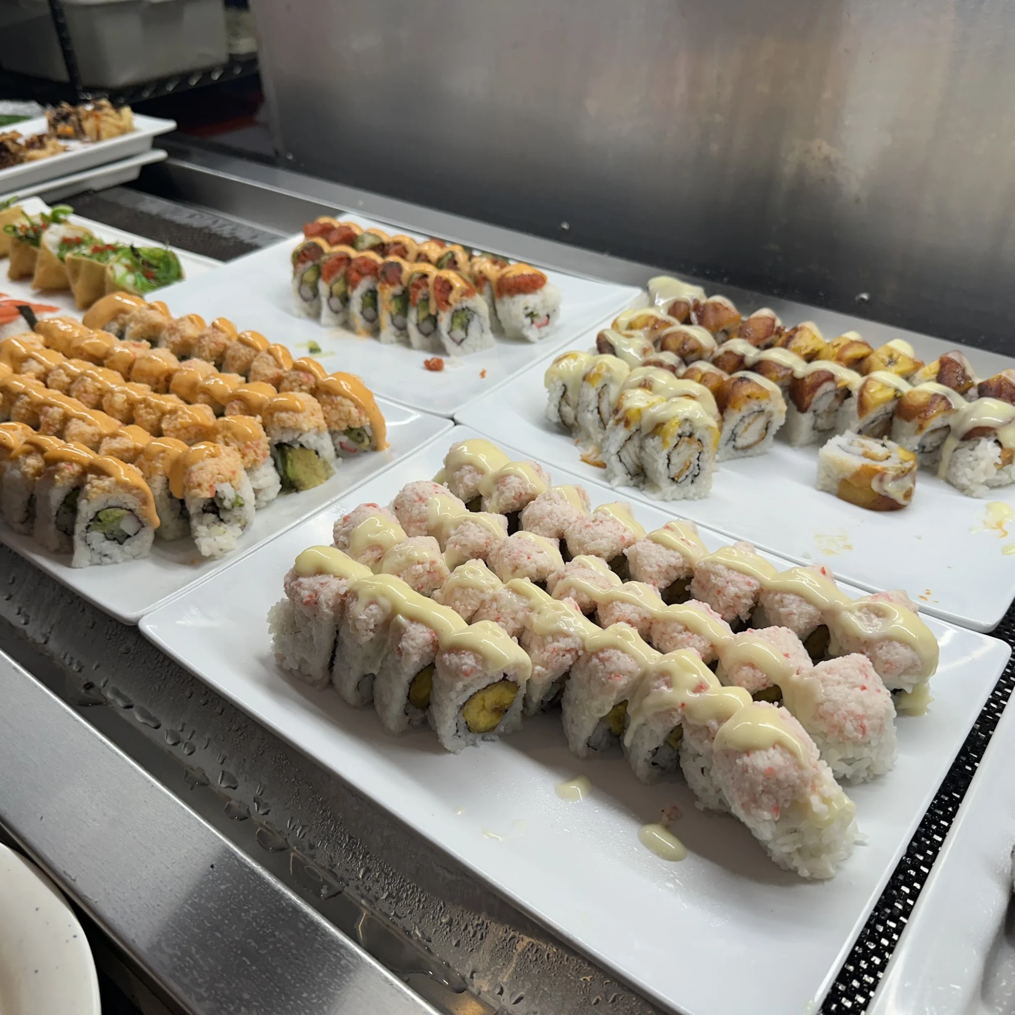 Various sushi rolls with sauces on white plates at Hibachi Grill & Supreme Buffet, Mott Haven.