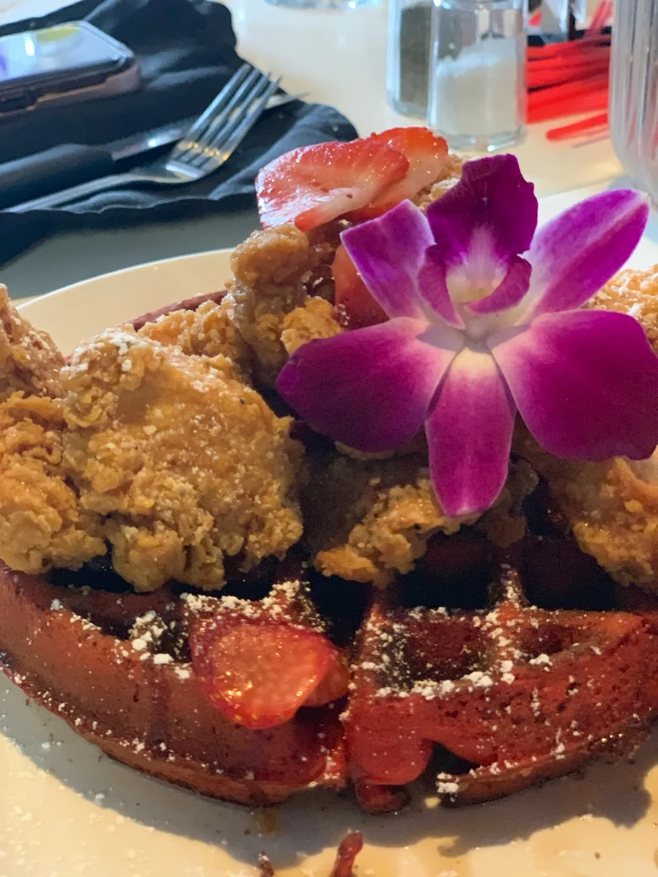 Fried chicken on waffles with strawberries and an edible flower at Que Rico Latin Cuisine, Parkchester.