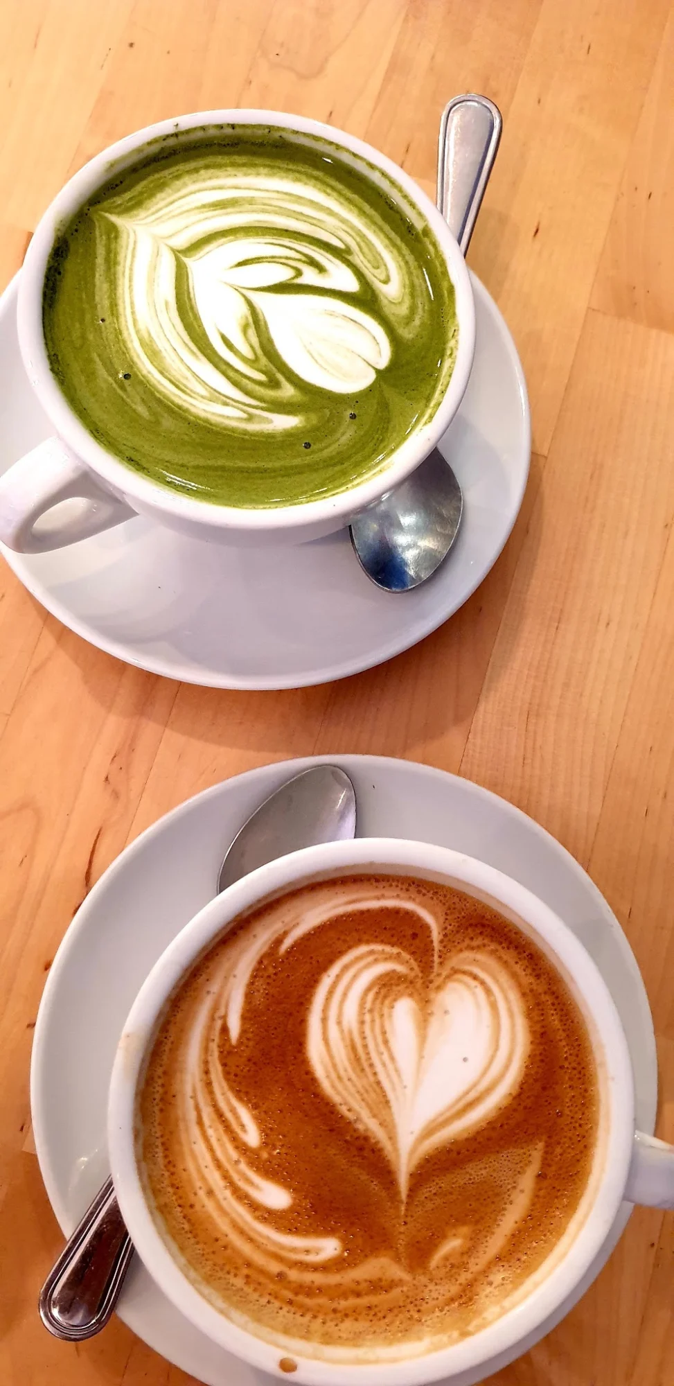 Absolute Coffee featured image Two cups of coffee with latte art on wooden table at Absolute Coffee, Bronx.