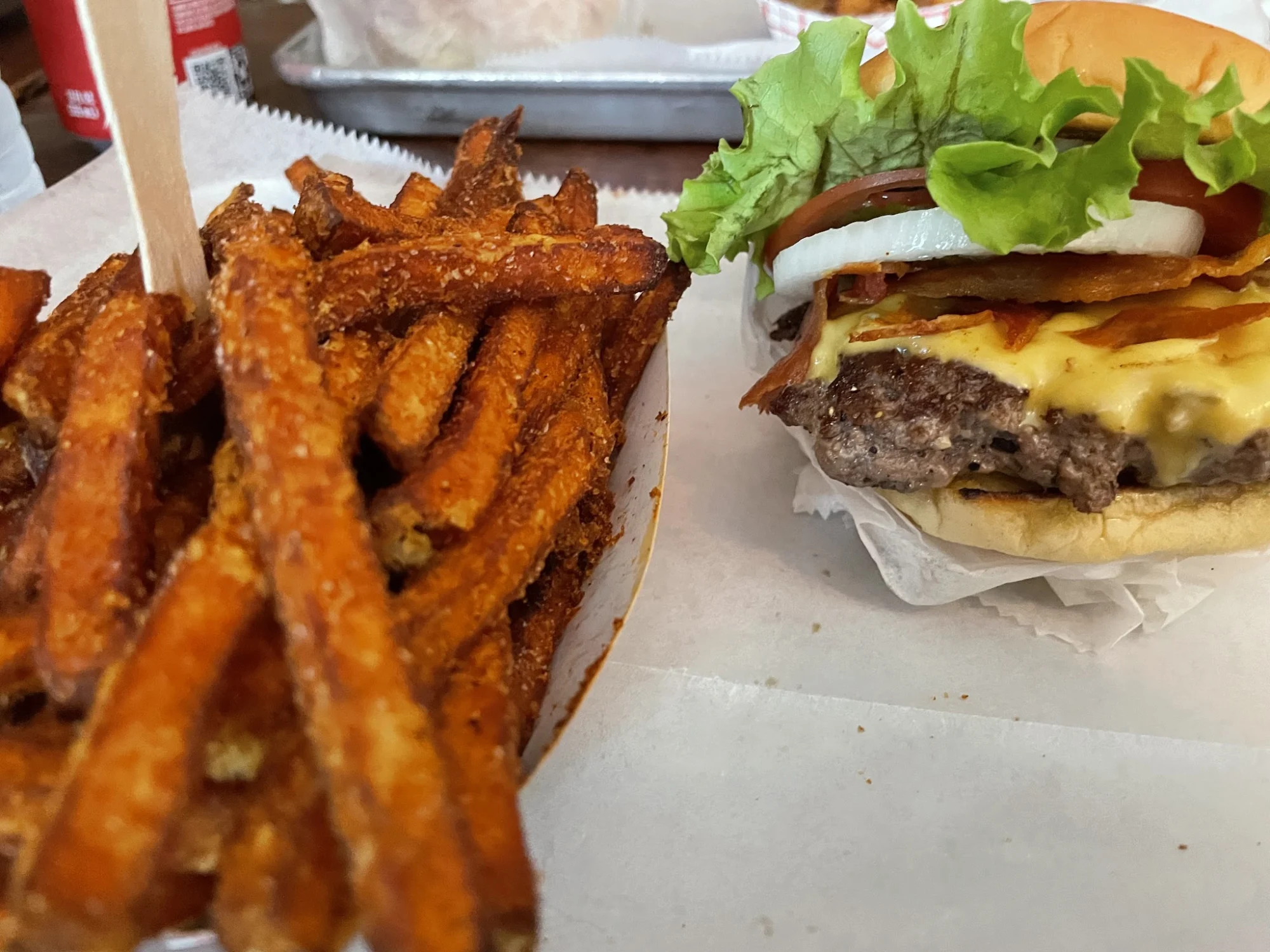 Milk Burger featured image Plate with seasoned fries and a cheeseburger topped with lettuce, tomato, and onion at Milk Burger, Mott Haven.