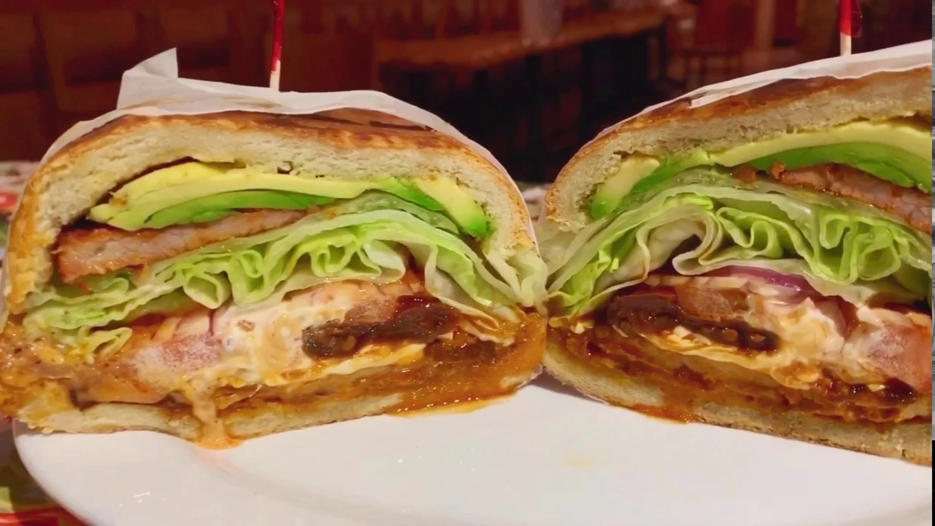 Close-up of a cut sandwich with avocado, lettuce, and meat from Nuevo Mexico, Park Slope.