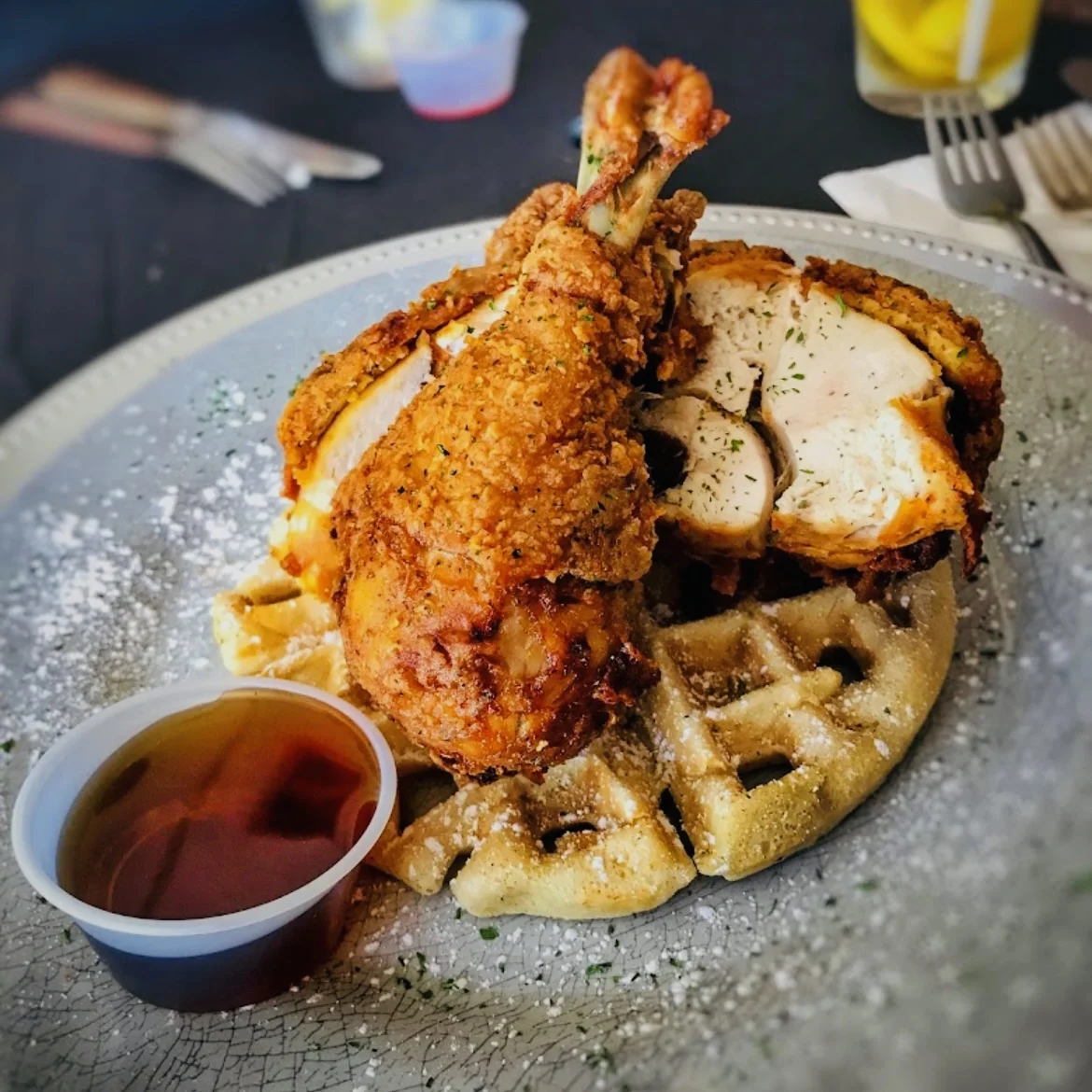 Sweet Potatoes Restaurant featured image Plate with fried chicken on waffles and a side of syrup at Sweet Potatoes Restaurant.