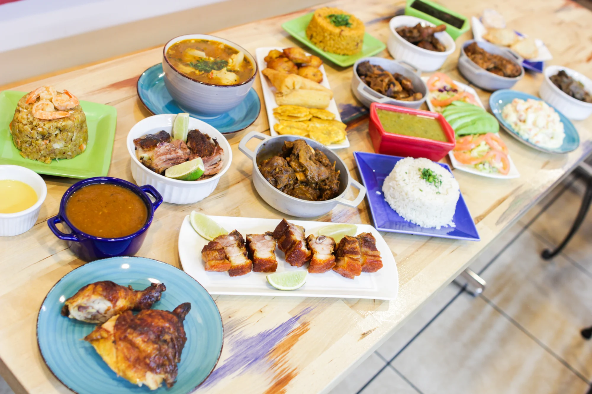 Morena's Kitchen Bar & Restaurant featured image A variety of dishes including meats, rice, and stews on a wooden table at Morena's Kitchen Bar & Restaurant, Corona.
