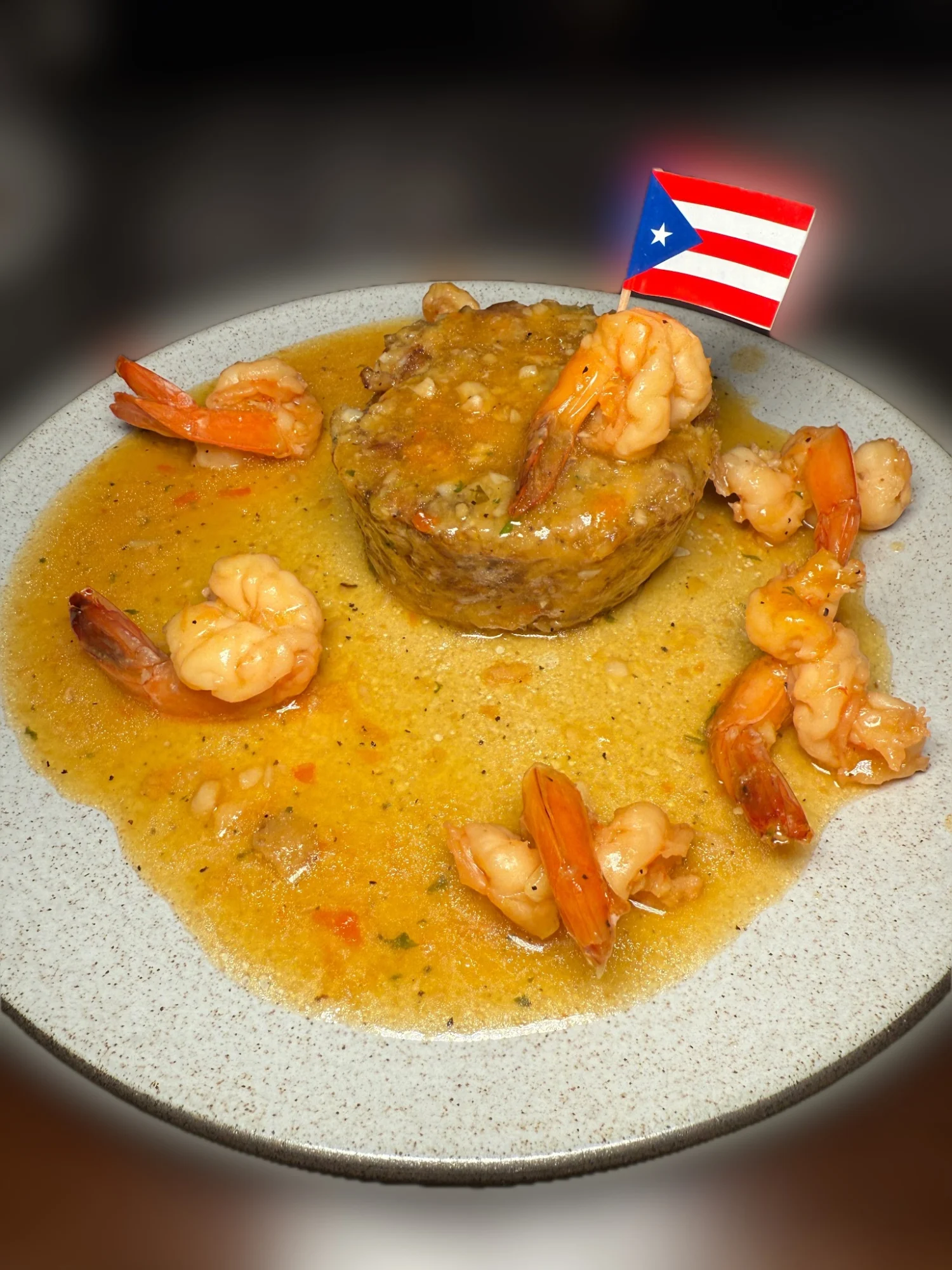 Plate with mofongo topped with shrimp and sauce, decorated with a small Puerto Rican flag at Boriken Restaurant & Bar, Stapleton.
