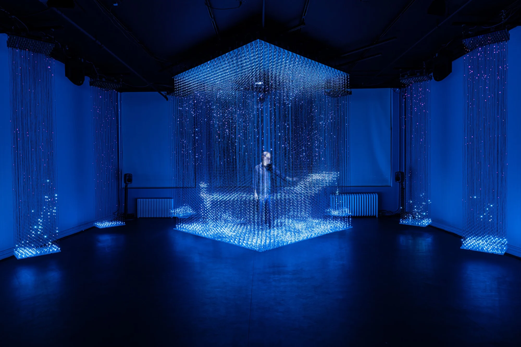 Blue illuminated art installation in a dark room at Onassis ONX, Tribeca.