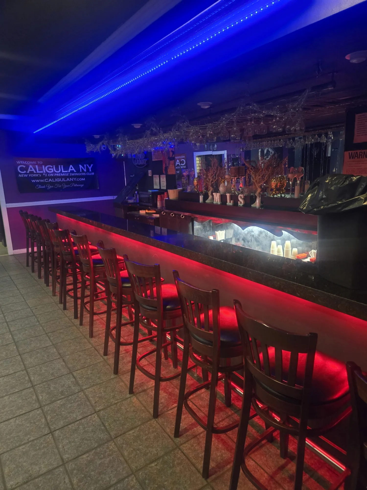 Interior bar with red lighting and chairs at Caligula, Astoria, Bronx NYC.