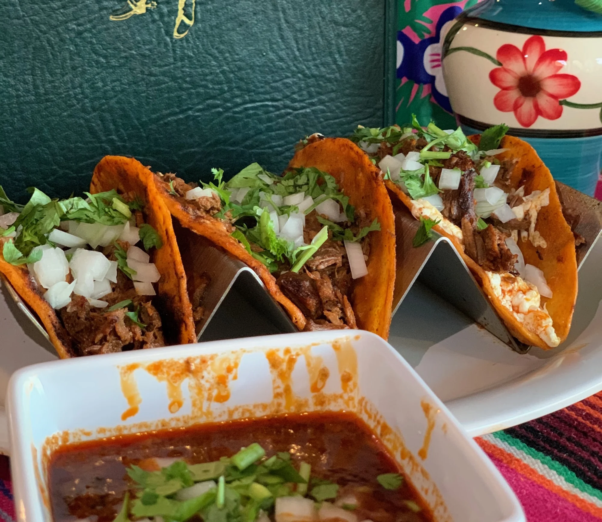 Close-up of tacos with meat, onions, and cilantro, served with a side of sauce at El Patron Restaurant & Lounge, Stapleton, Bronx NYC.