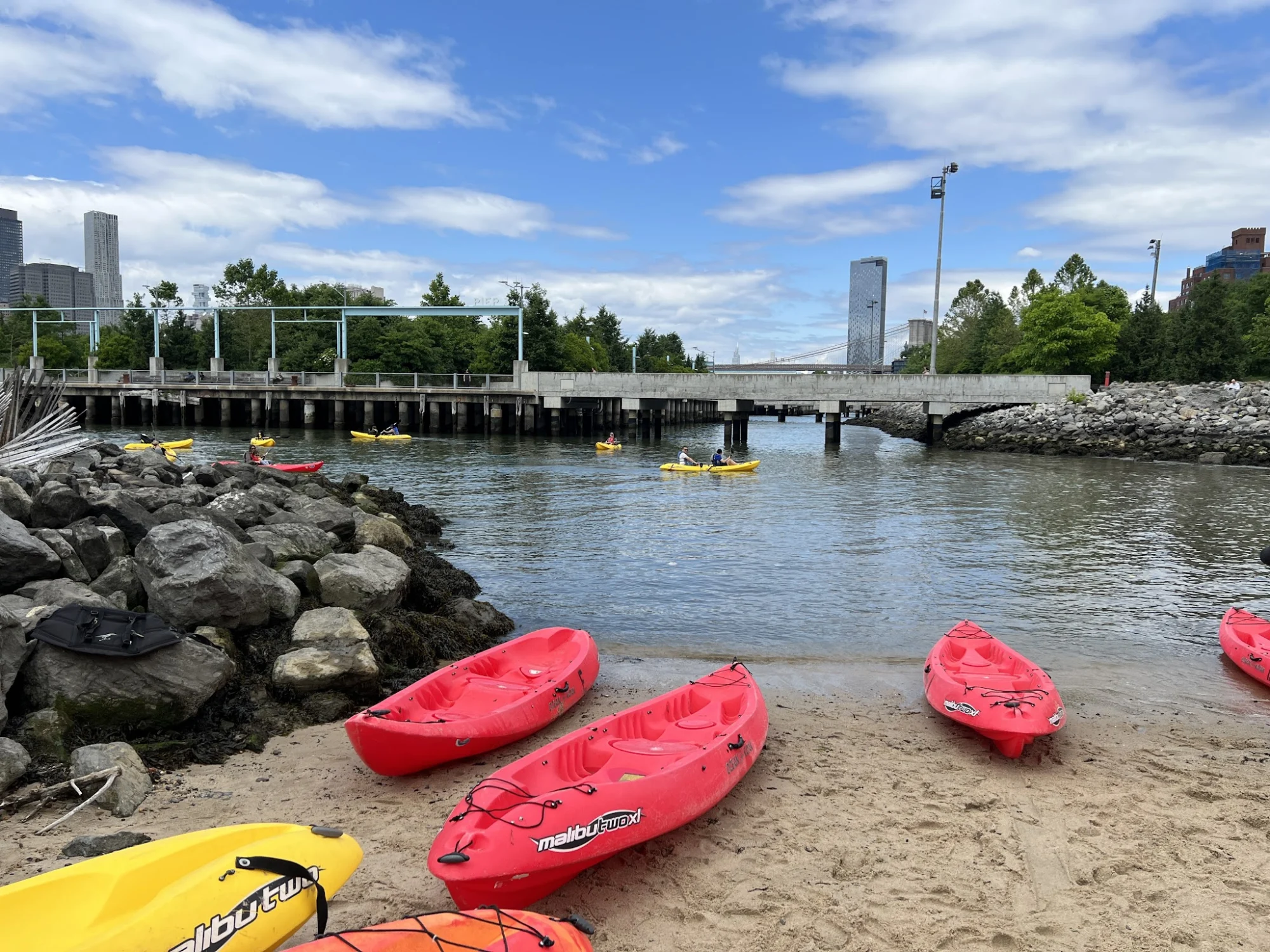 Kayaks on the sandy shore with a view of the pier at Pier 4 Beach, DUMBO, Bronx NYC.