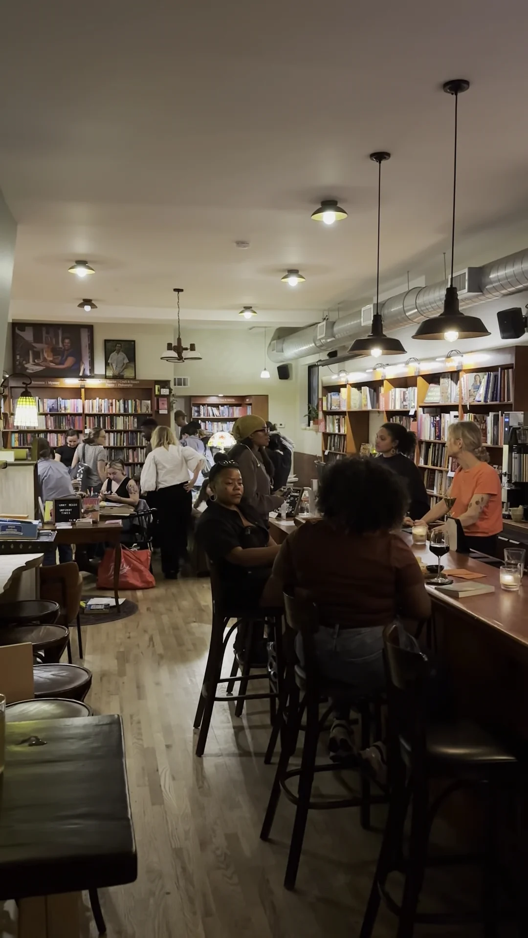 Interior of Liz's Book Bar in Carroll Gardens with people gathered around tables, bookshelves lining the walls.
