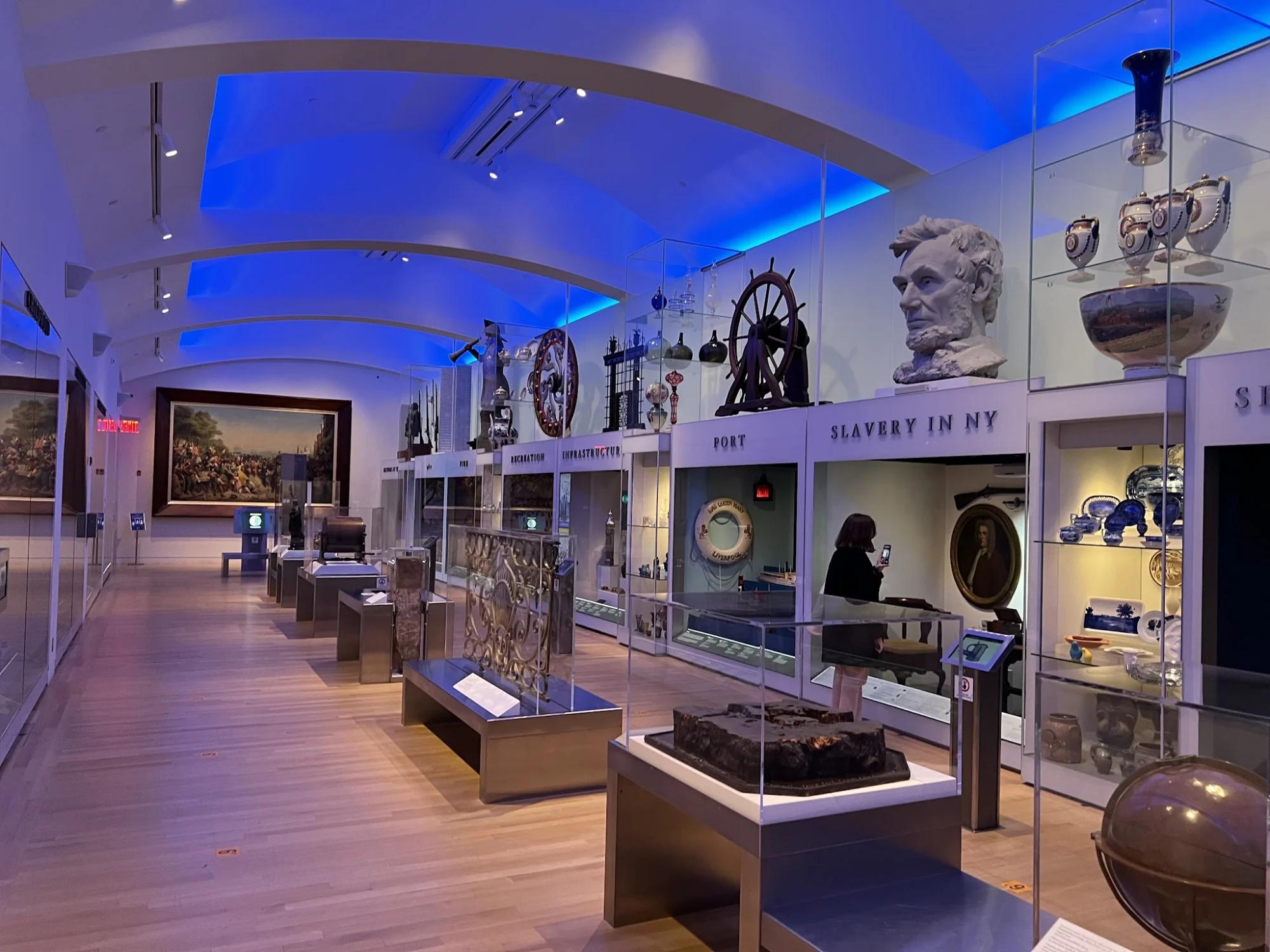 Gallery with blue lighting and historical exhibits, including maritime artifacts and a bust, New York Historical, Upper West Side.