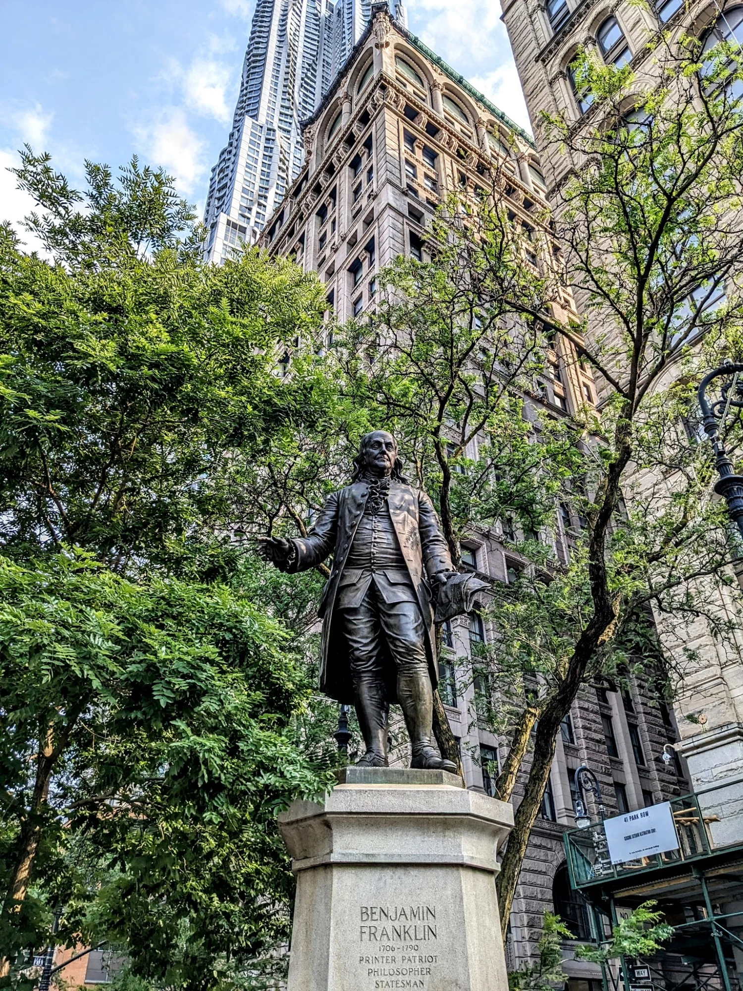 Benjamin Franklin Statue with trees and buildings in Financial District, Bronx NYC.