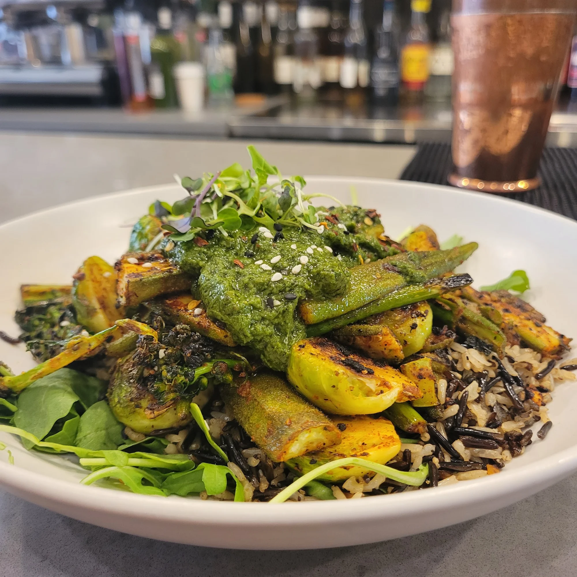 Bowl of rice topped with green vegetables and sauce at Aunts et Uncles, Flatbush.
