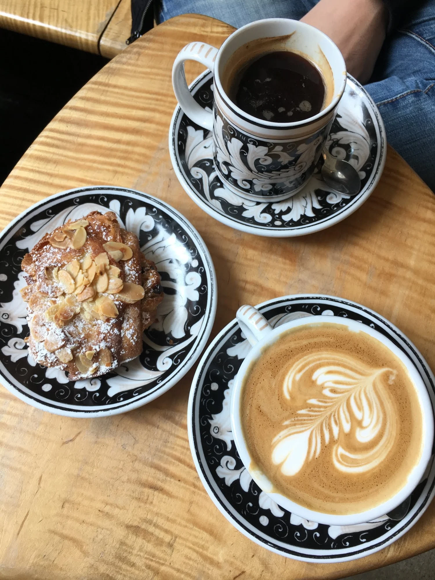 La Colombe Coffee Workshop featured image Table with two coffees and an almond pastry on decorative black and white plates at La Colombe Coffee Workshop, SoHo.