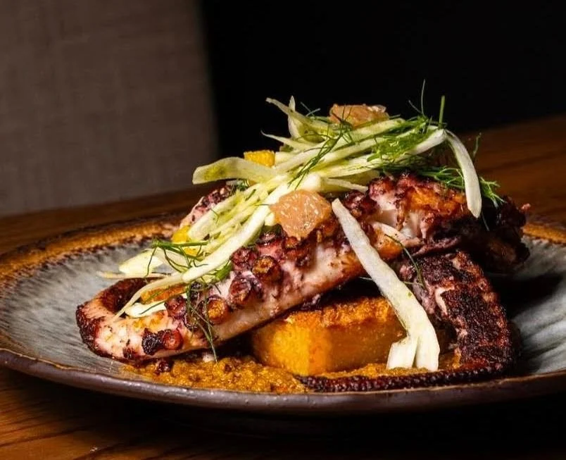 Grilled octopus with sliced fennel and orange on a ceramic plate at BOKAGUÁ, Riverdale Bronx NYC.