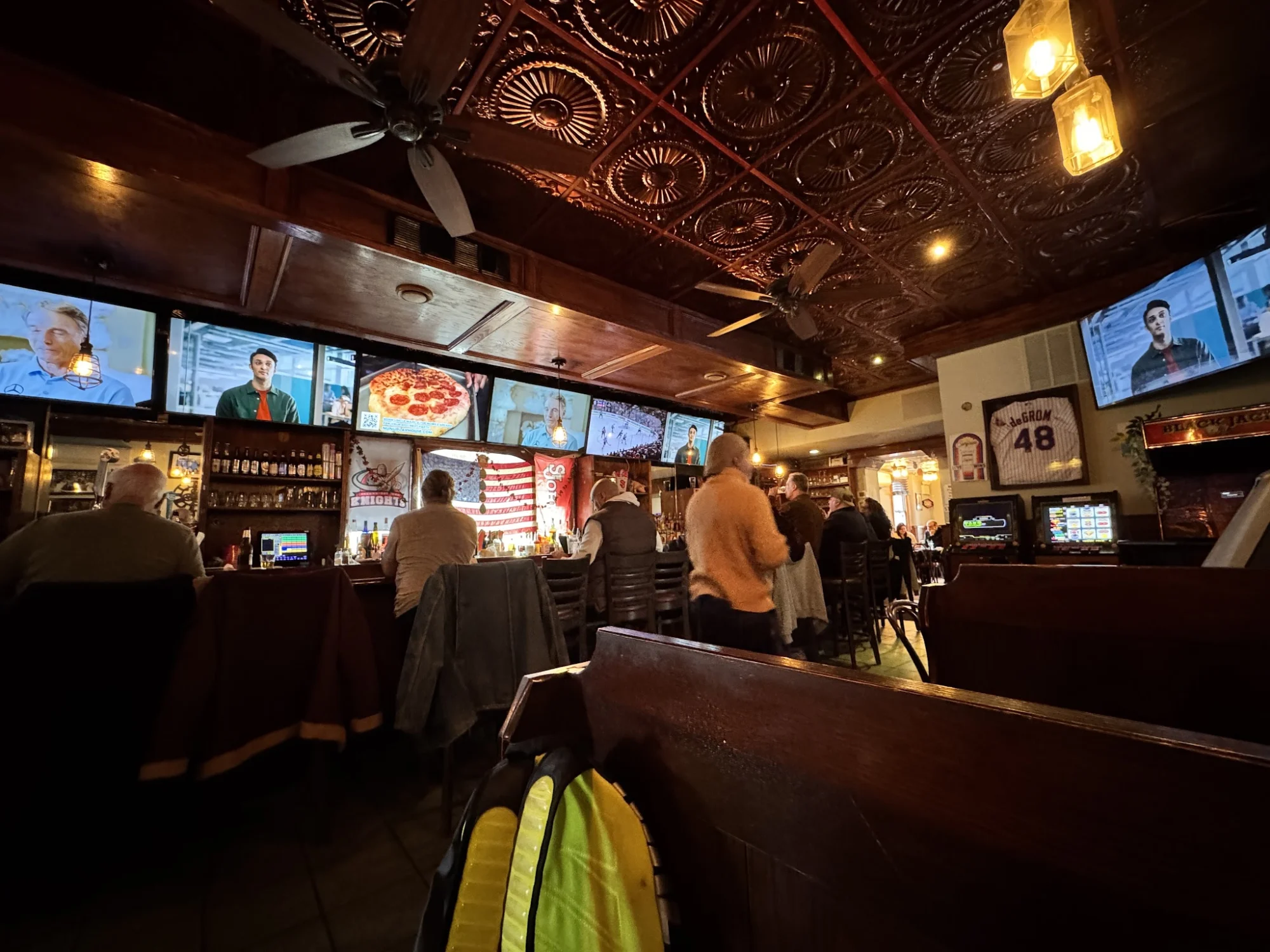 Fillmore's Tavern featured image Dimly lit interior of Fillmore's Tavern, Fresh Meadows, with patrons at the bar and multiple TVs on the walls.
