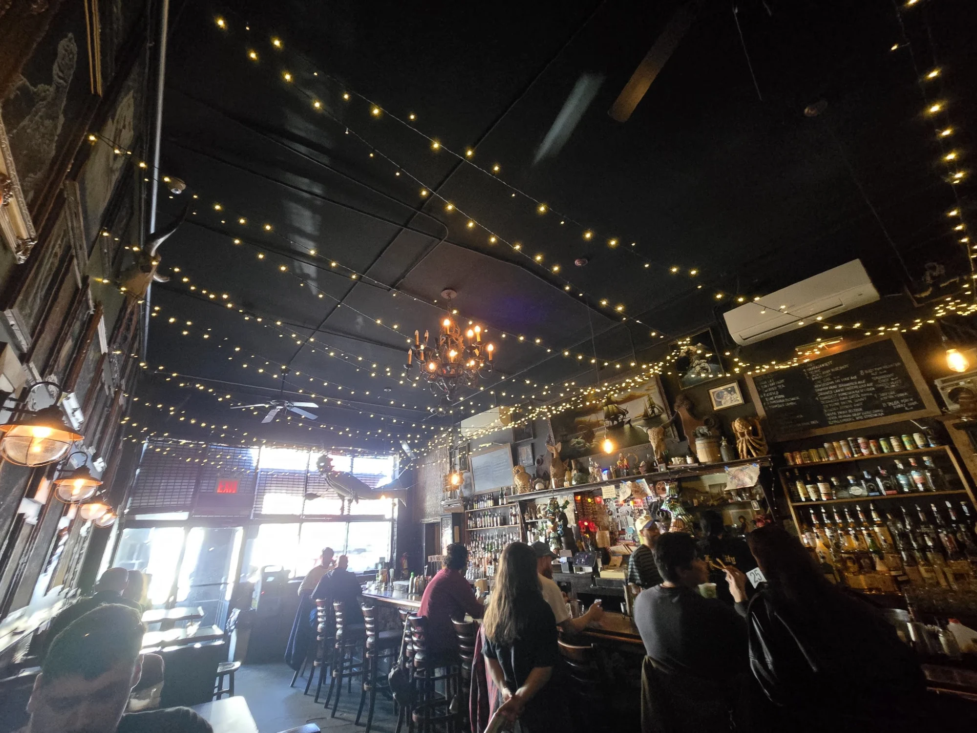 Interior of The Anchored Inn, East Williamsburg, Bronx NYC with a bar area, string lights, and patrons.