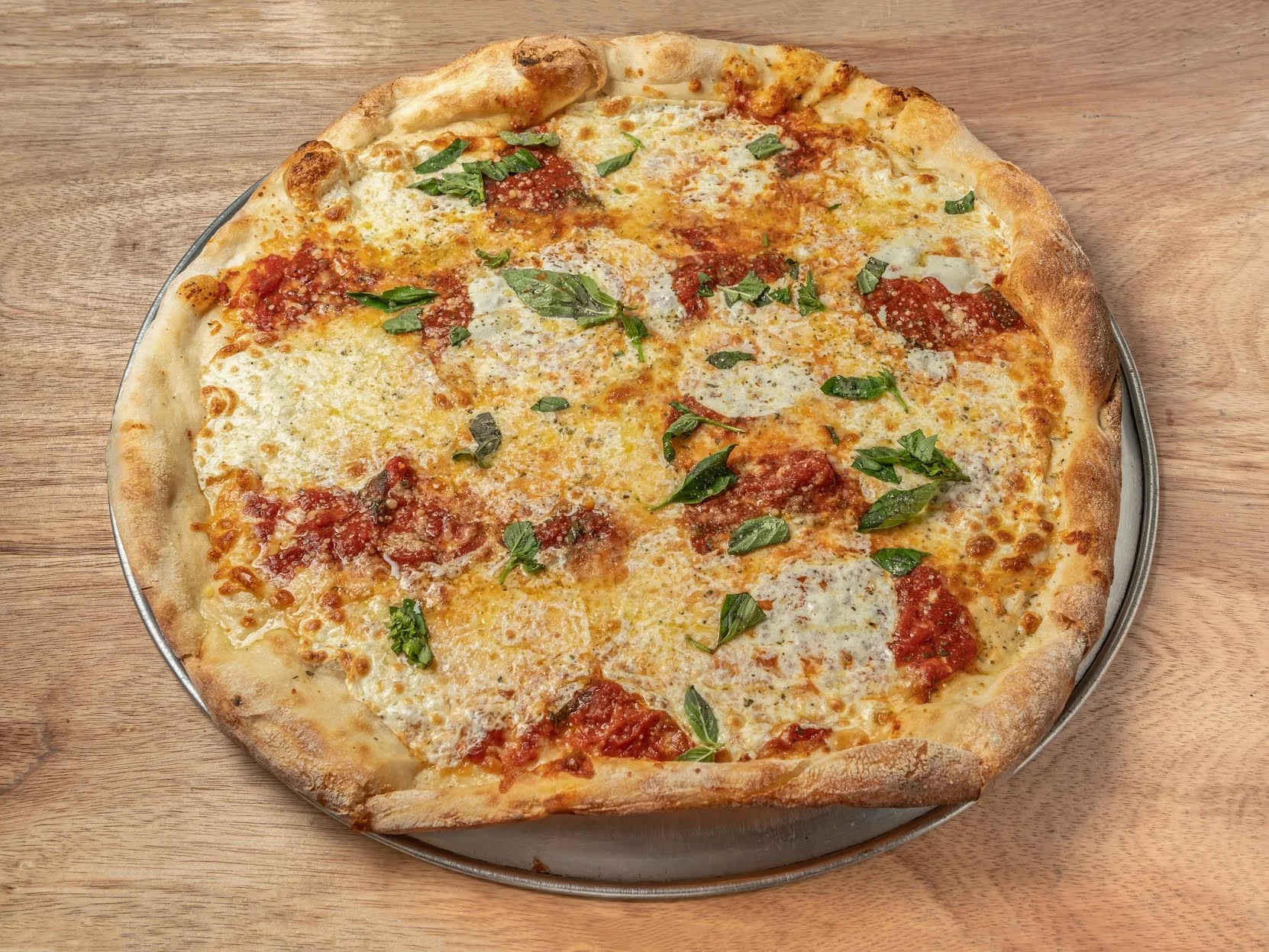 Angie's Cafe & Pizza featured image A round pizza topped with cheese, tomato sauce, and fresh basil at Angie's Cafe & Pizza, Mott Haven Bronx NYC.