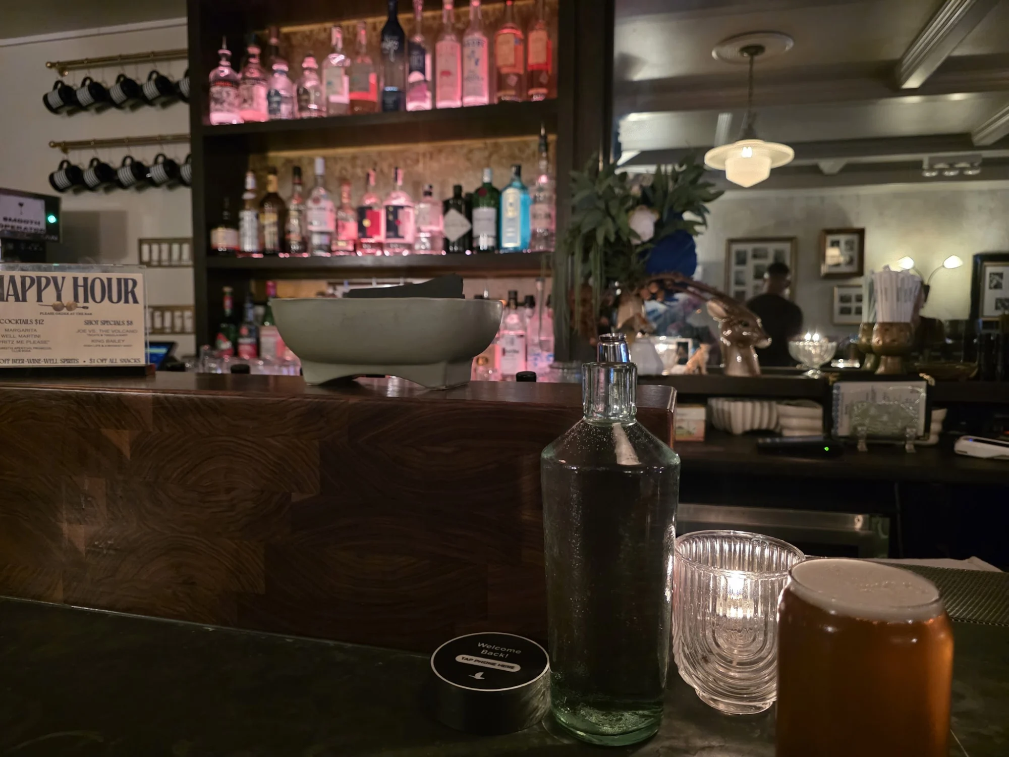 MIDNIGHTS featured image Bar counter with various bottles and dim lighting at MIDNIGHTS, Williamsburg.