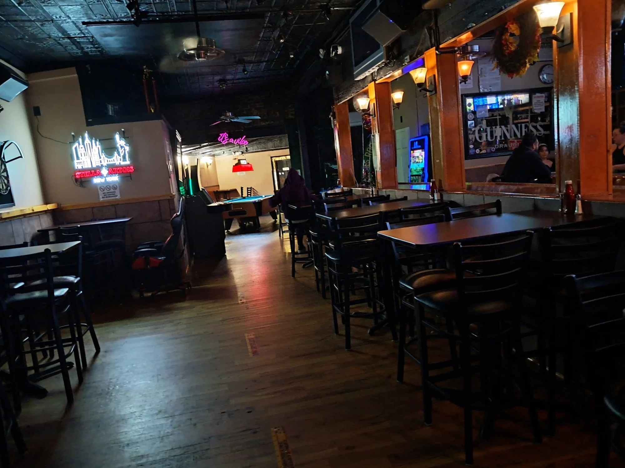 Interior view of B.B.'S Pub and Grill, Flushing. Dimly lit bar with high tables and neon signs.