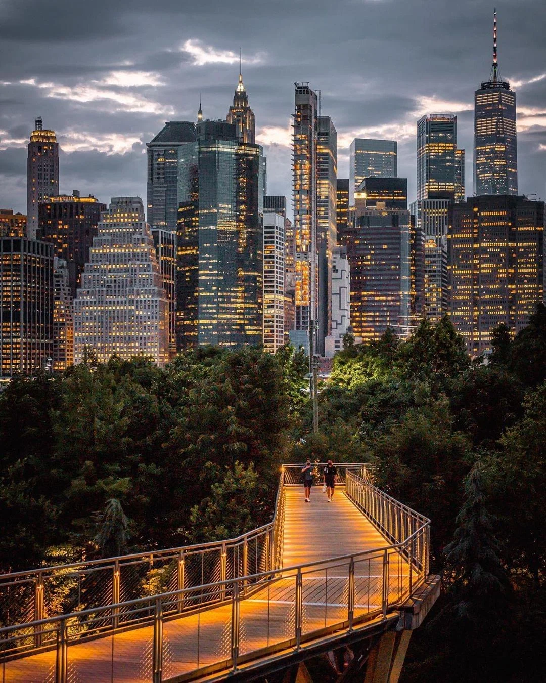 View of Manhattan skyline from Squibb Park with illuminated pathway at dusk, Brooklyn Heights.