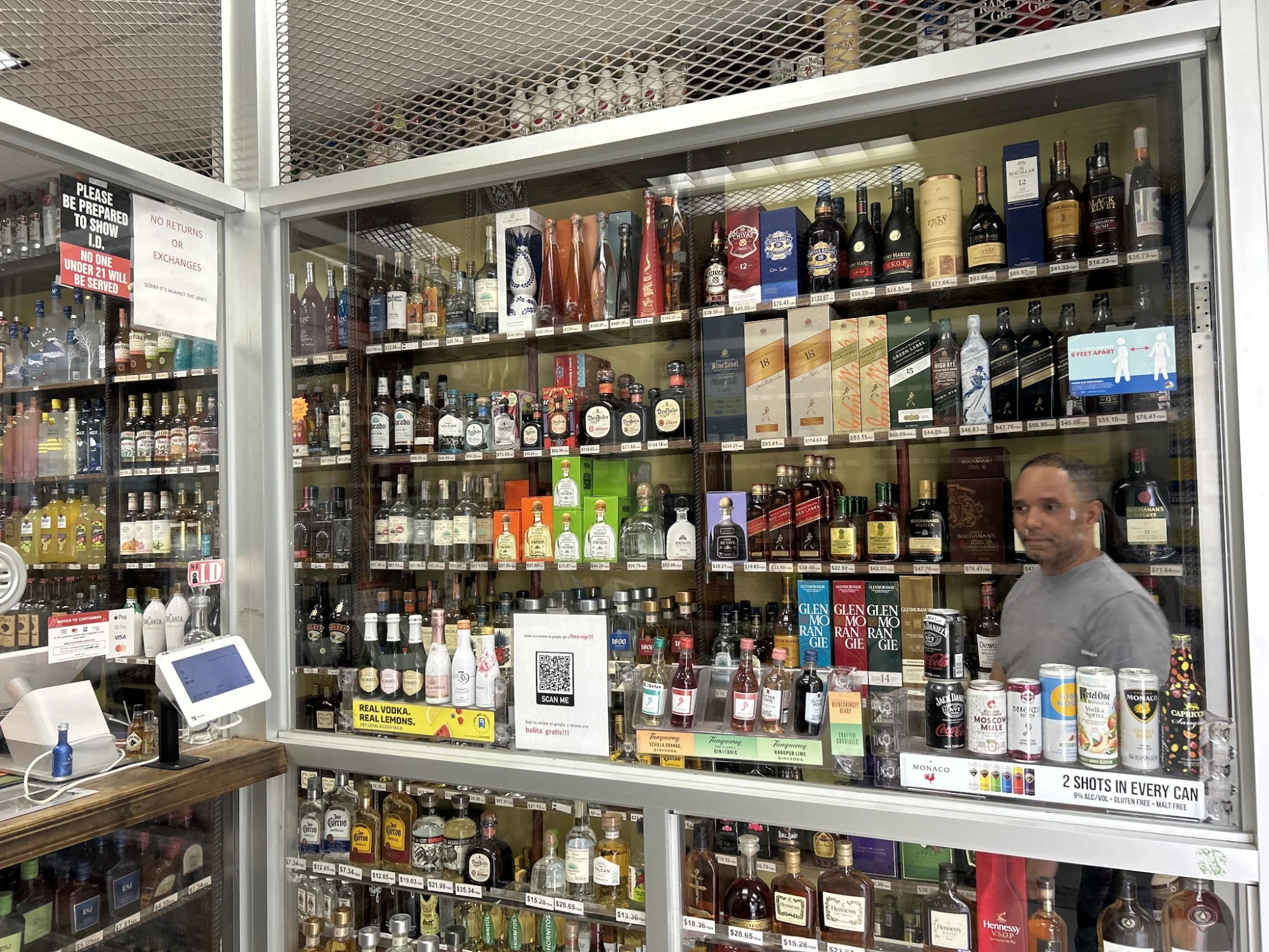 Interior of Chris Liquor Store, Belmont, with shelves of various liquor bottles behind a glass counter.