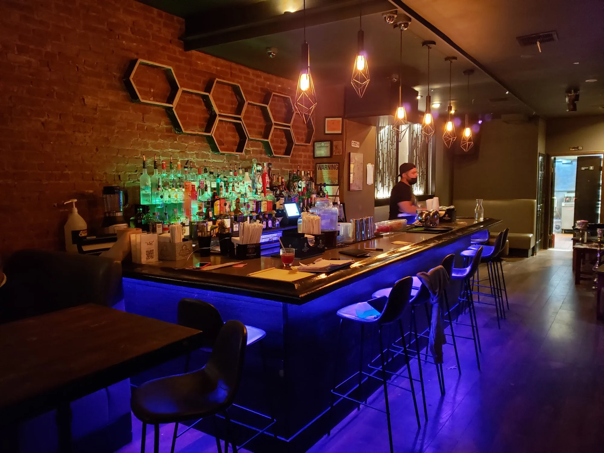The Spot Astoria bar interior with brick wall, bar stools, and hanging lights, Astoria, Bronx NYC.