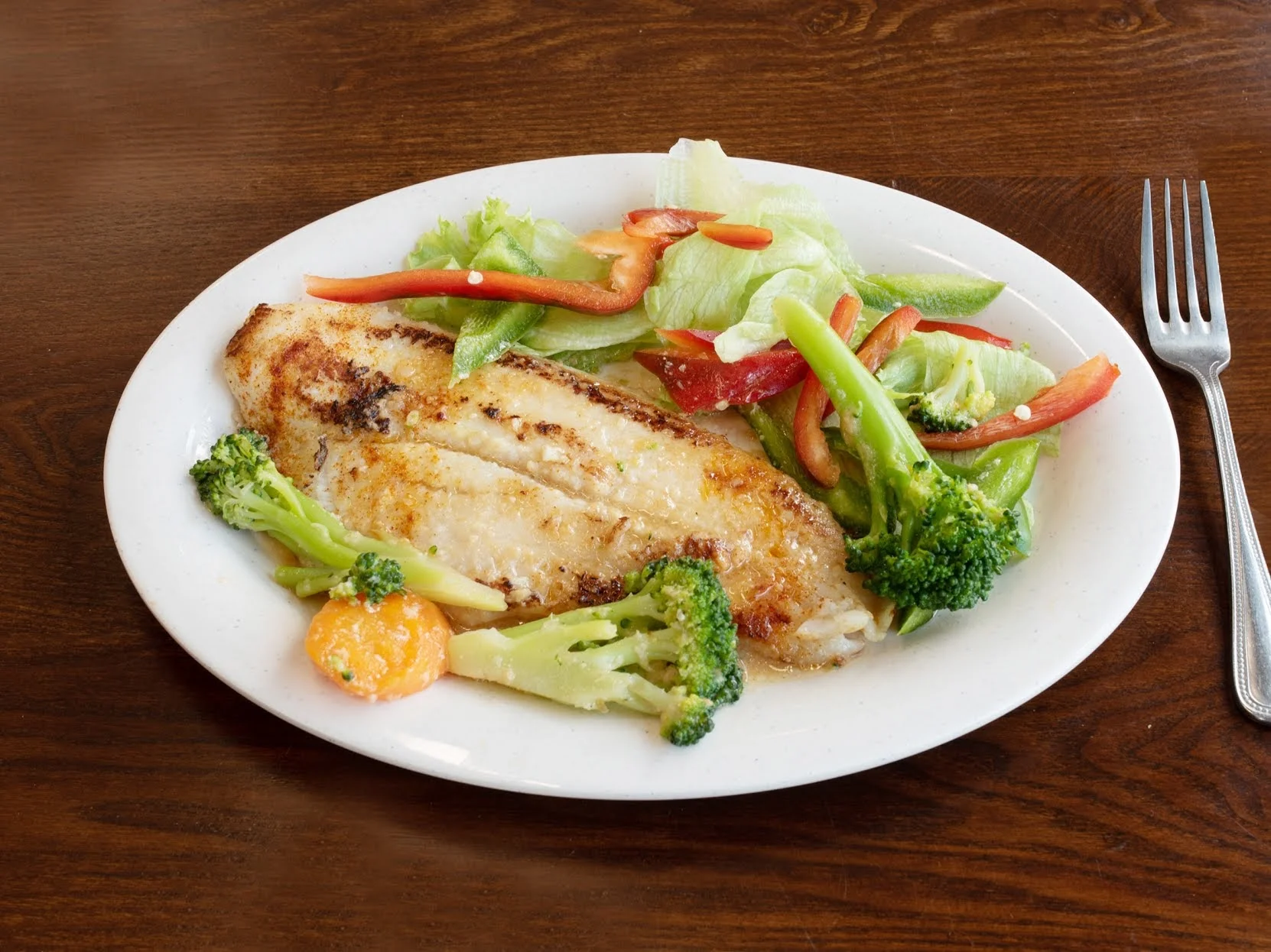 Grilled fish with broccoli, lettuce, and peppers on a white plate at Campeon Del Pollo, Corona.