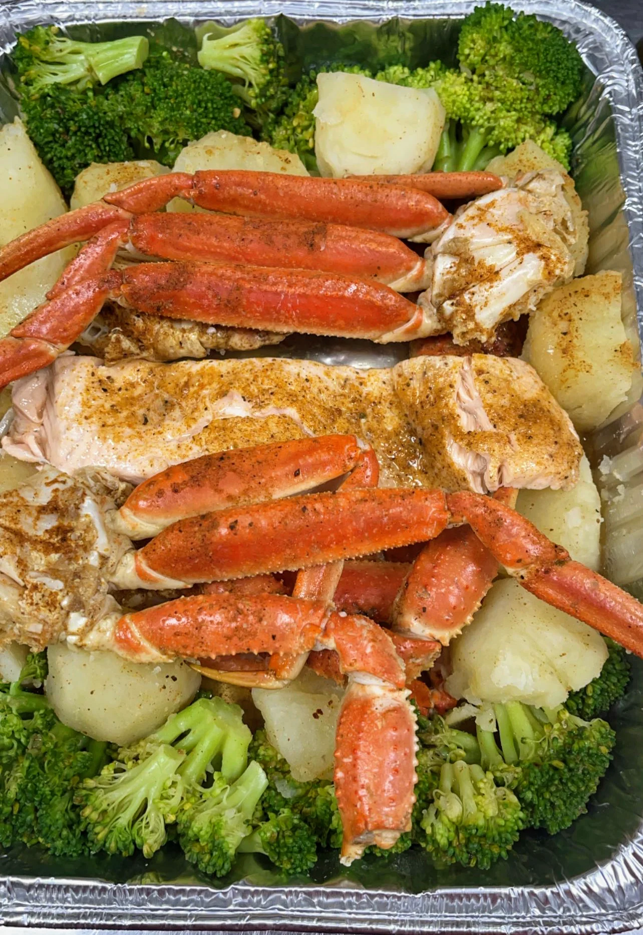 Junction Seafood Restaurant / Fast & Fresh Comida Típica featured image Tray of seafood with crab legs, salmon, broccoli, and potatoes at Fast & Fresh Comida Típica, Jackson Heights.