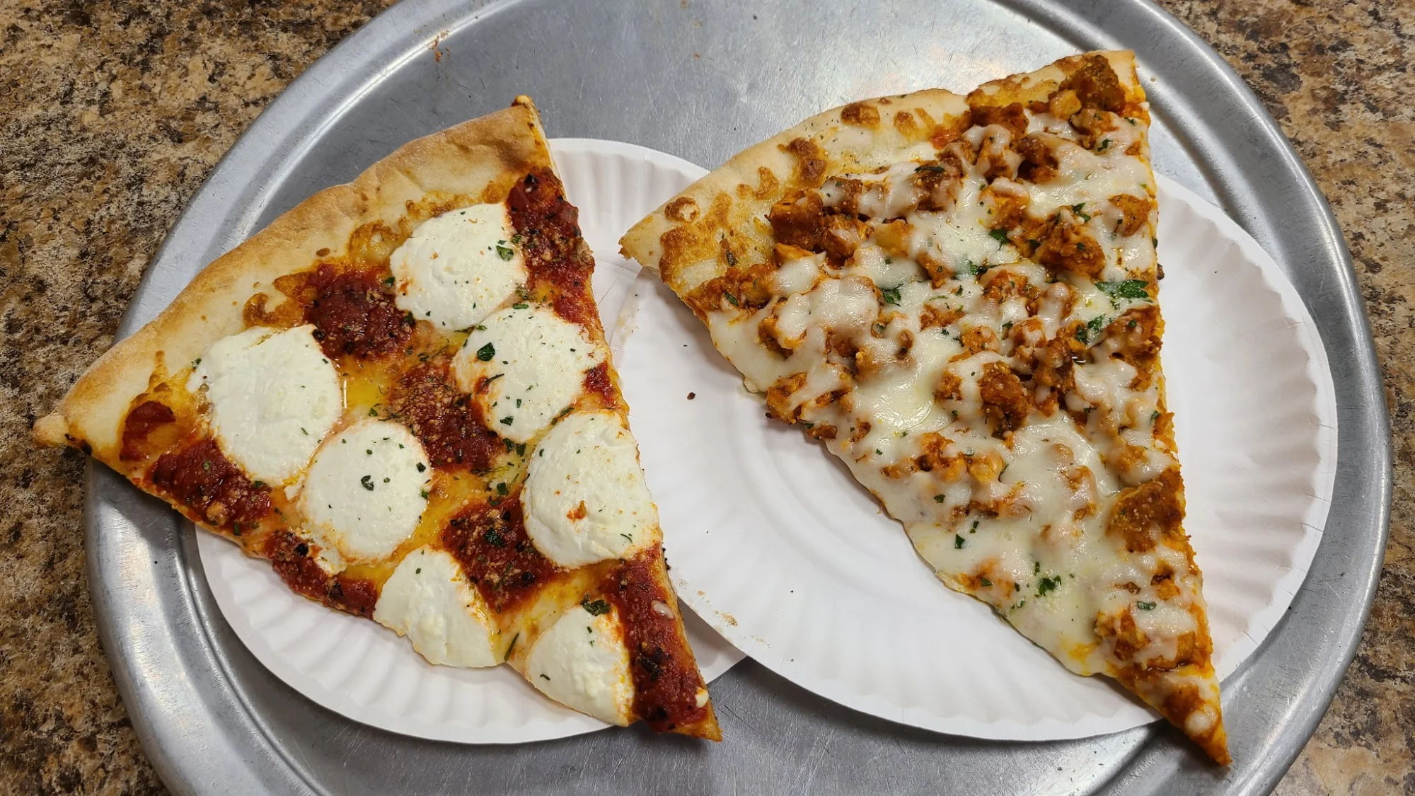 Pelham Pizza featured image Two pizza slices on paper plates: one with cheese and sauce, one with chicken and cheese at Pelham Pizza, Bronx NYC.