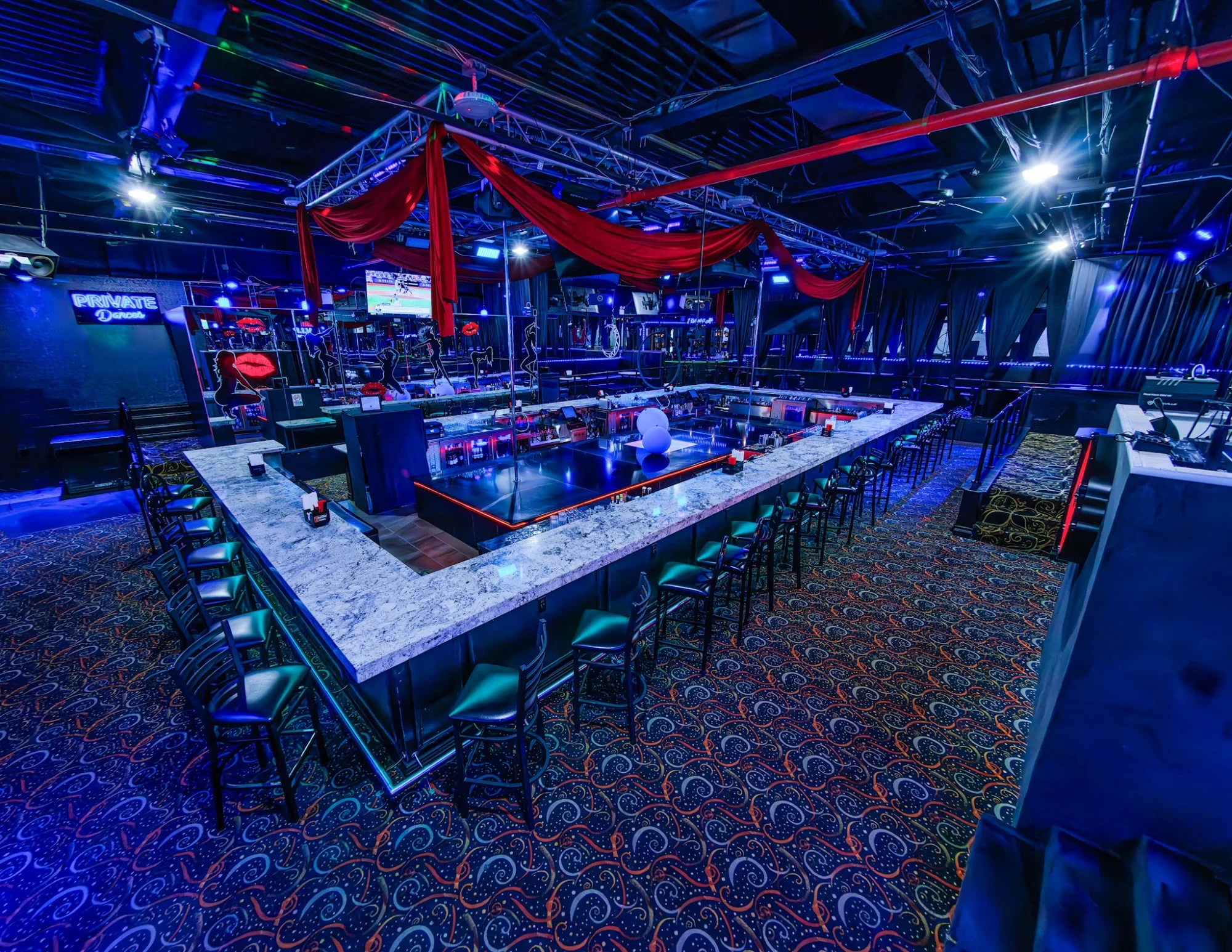 Interior of Ten's Cabaret in Bronx NYC showing a spacious bar area with a central stage and neon lighting.