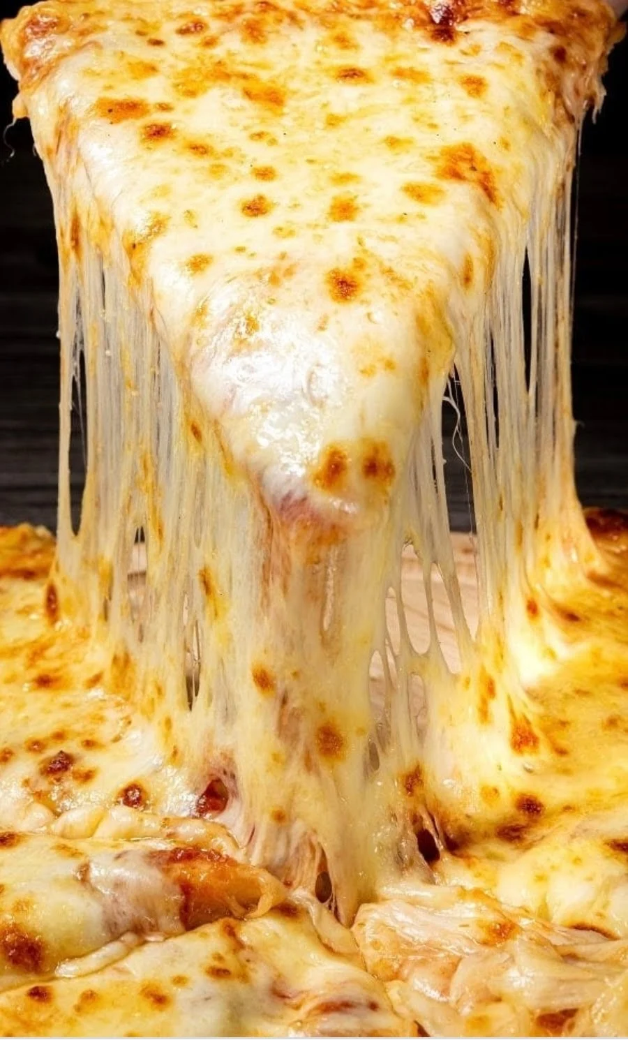 Close-up of a cheese pizza slice being lifted, with melted cheese stretching at Rocco's Pizzeria, Bedford Park.