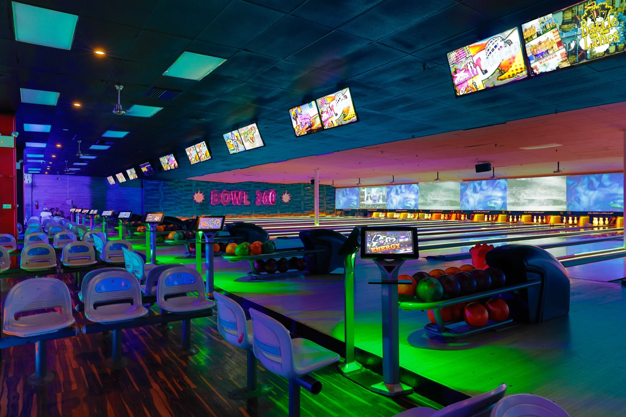 Bowling lanes with colorful lighting and monitors at Bowl 360 Ozone Park.