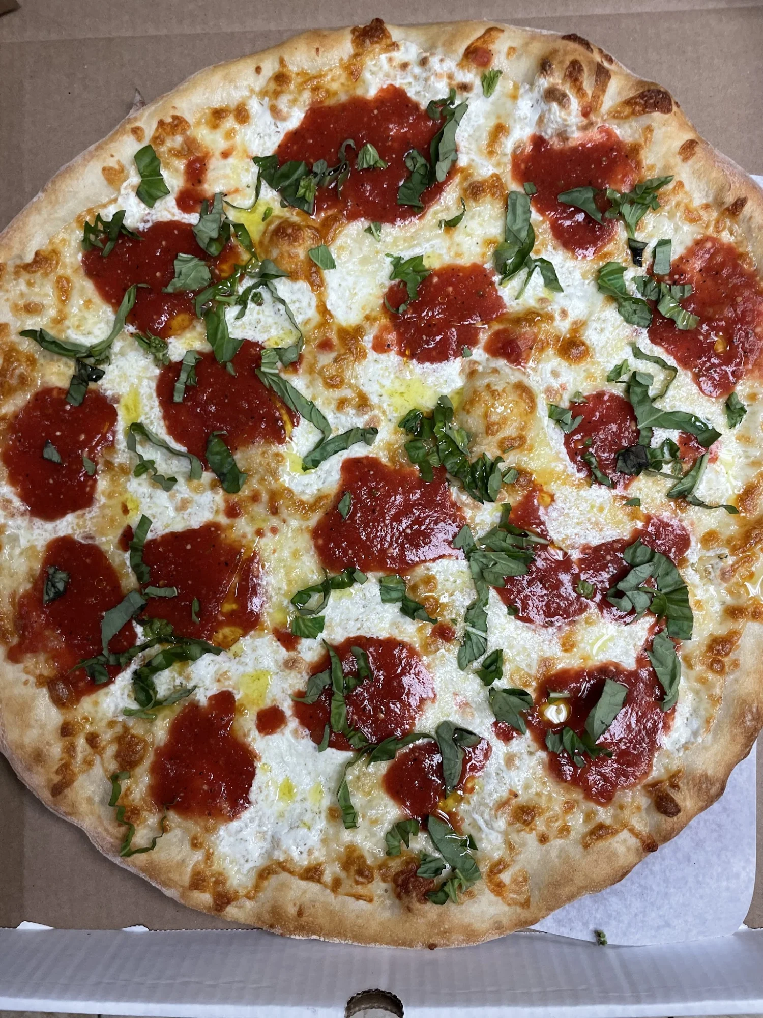 Close-up of a pizza with red sauce dollops, basil, and melted cheese at Marconi’s Pizzeria in Norwood, Bronx.