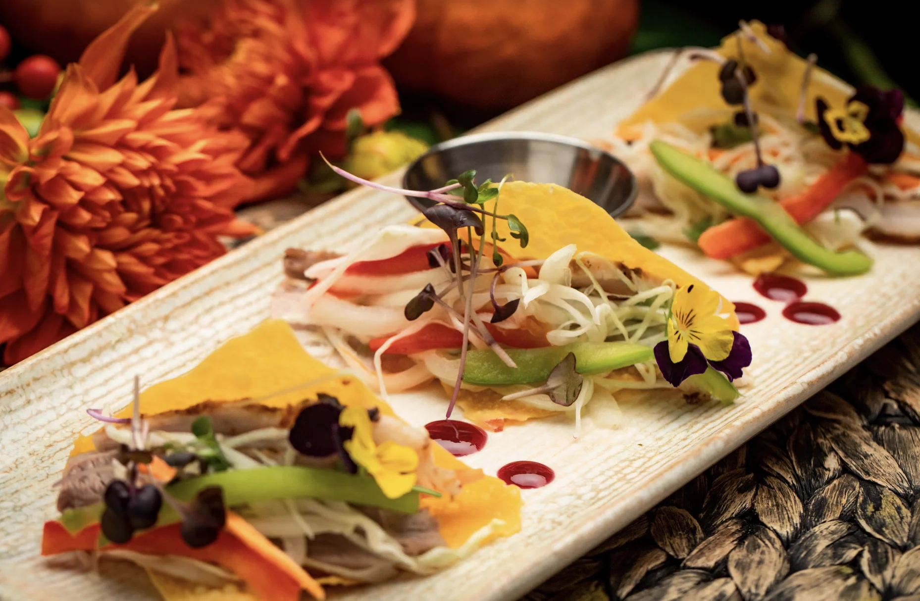 Three vibrant tacos with colorful toppings on a rectangular plate at Kokomo Restaurant & Lounge, Williamsburg.