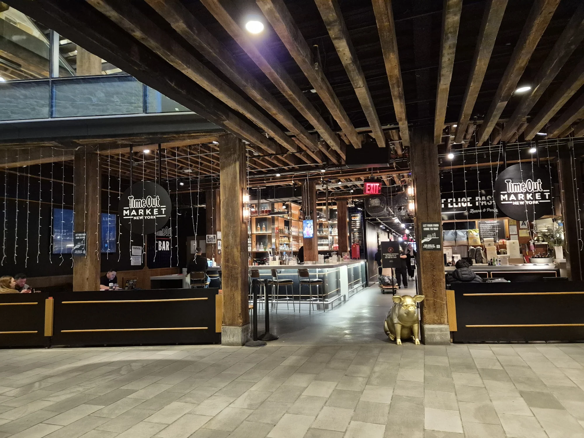 Interior of Time Out Market New York in DUMBO, showing an open space with wooden beams and seating areas.