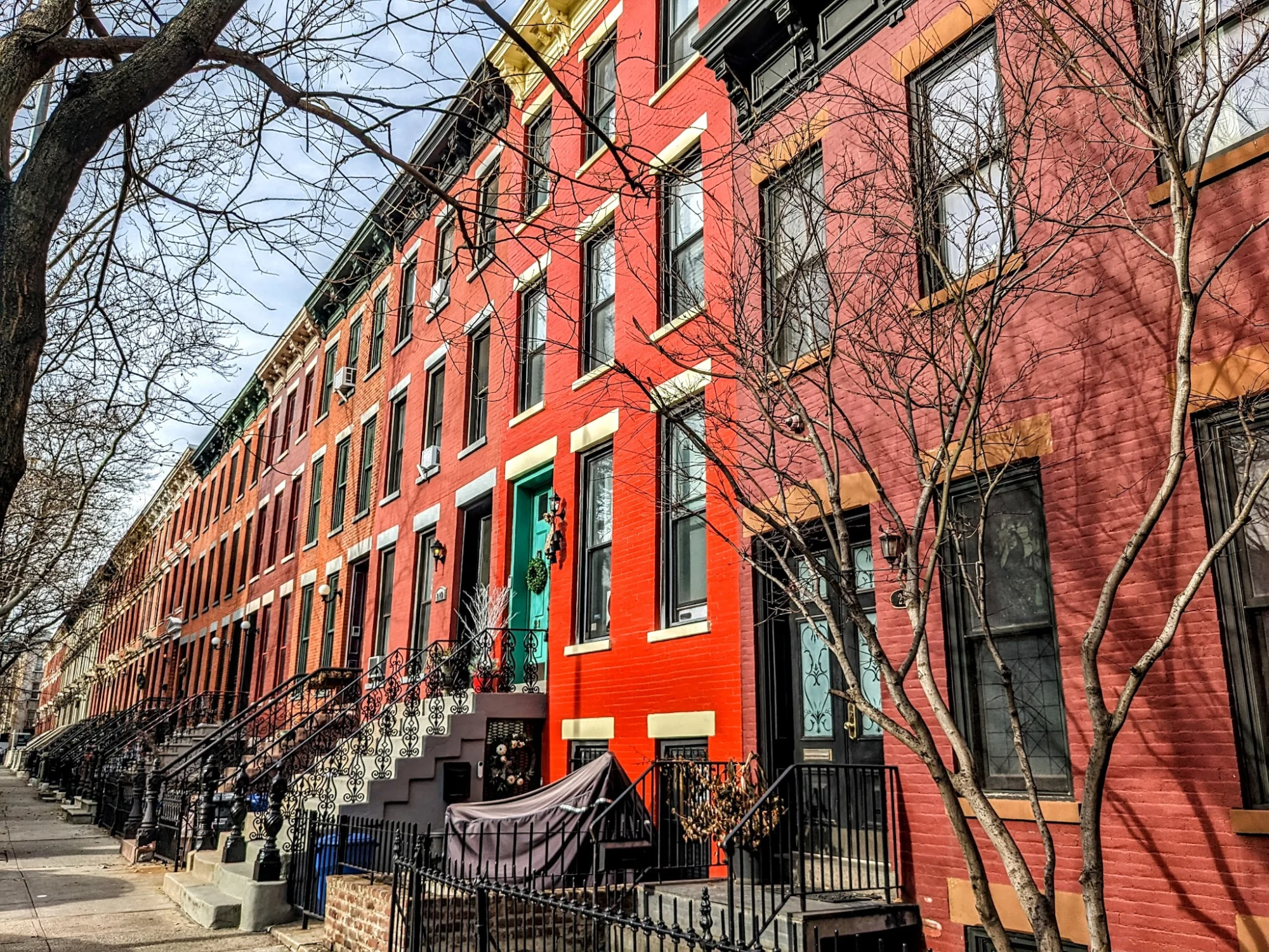 Row of colorful brownstones with red facades in Hunters Point Historic District.