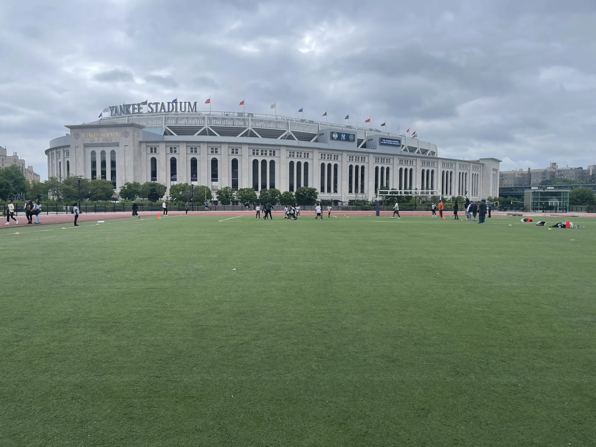 Wide view of Macombs Dam Park showcasing open green fields and Yankee Stadium in Concourse, Bronx NYC.