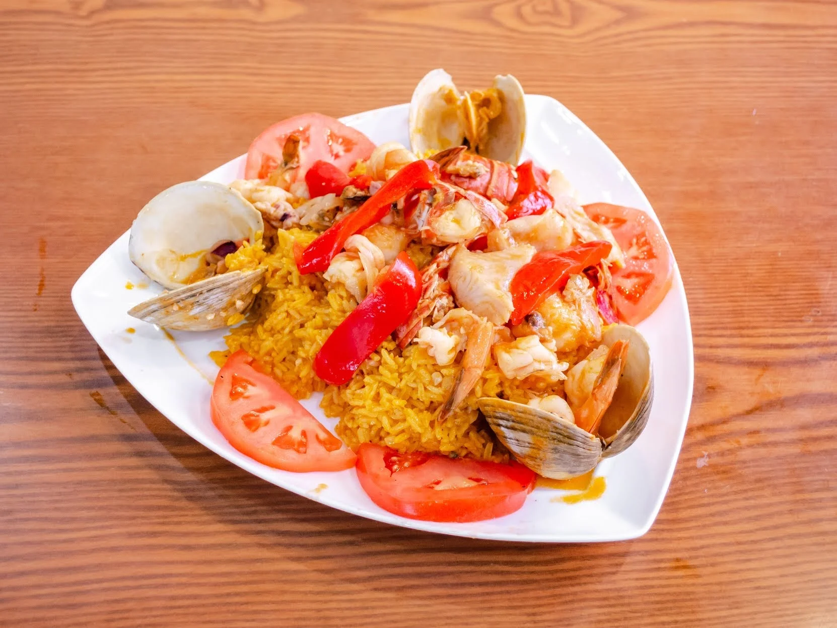 Seafood dish with clams, rice, tomatoes, and red peppers on a white plate at El Nuevo Carribeno, East Harlem.