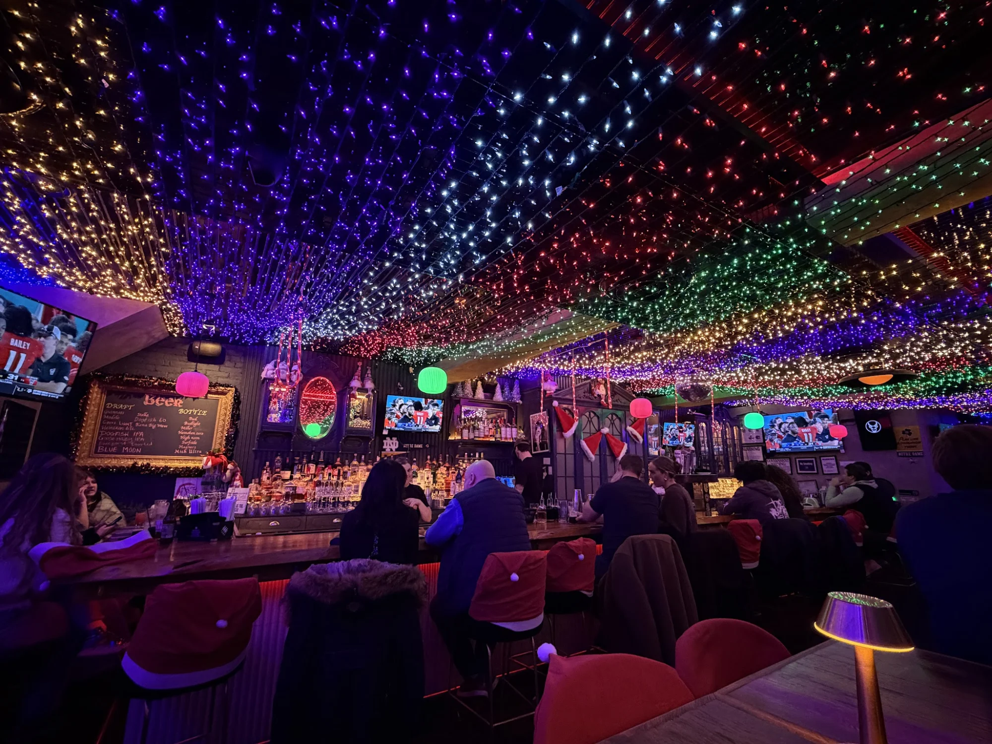 Seven Sins Bar featured image Interior of Seven Sins Bar, Kips Bay, with colorful lights and patrons seated at the bar.