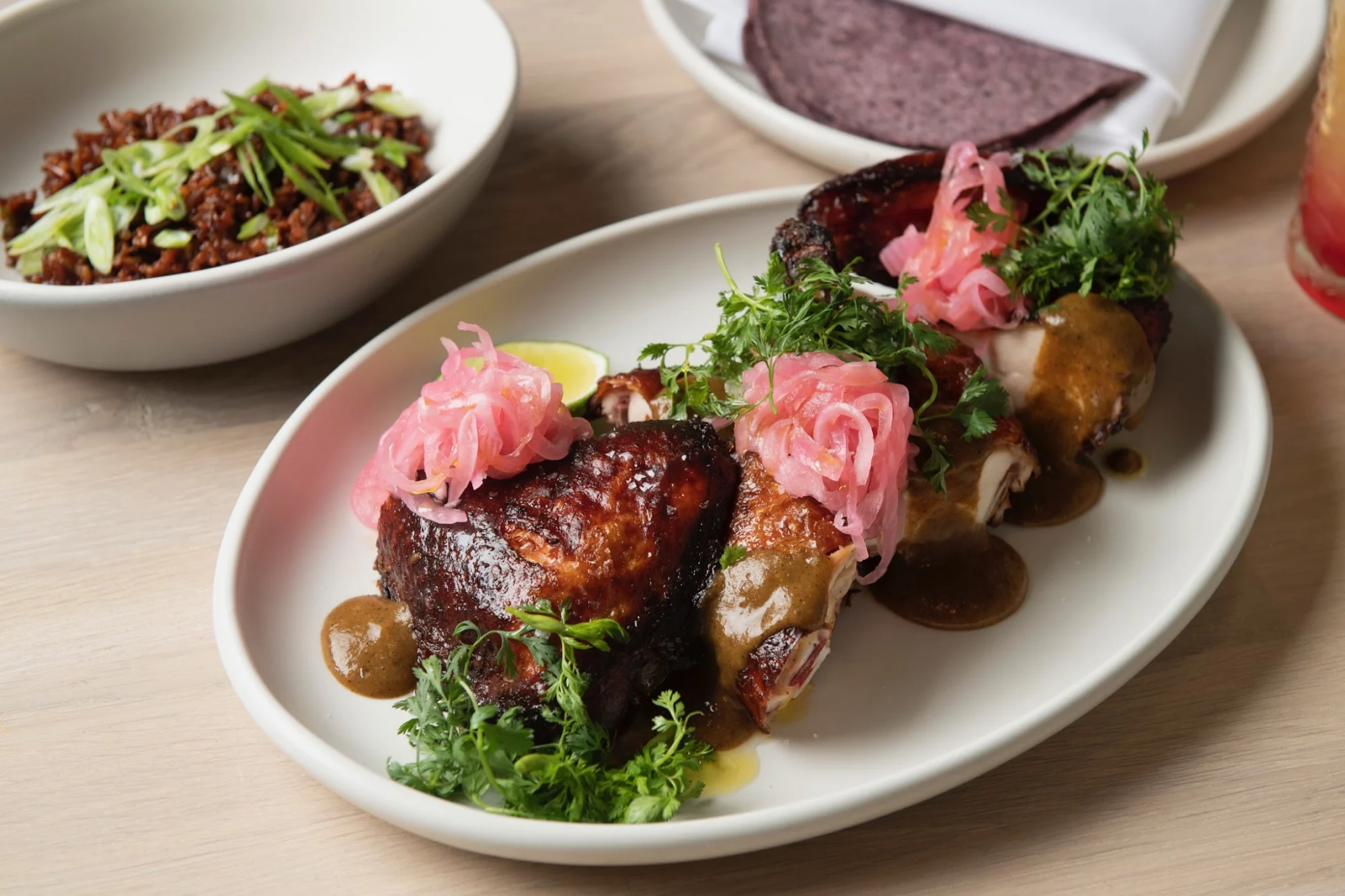Close-up of a plate with grilled meat and pink pickled onions at Oxomoco, Greenpoint.