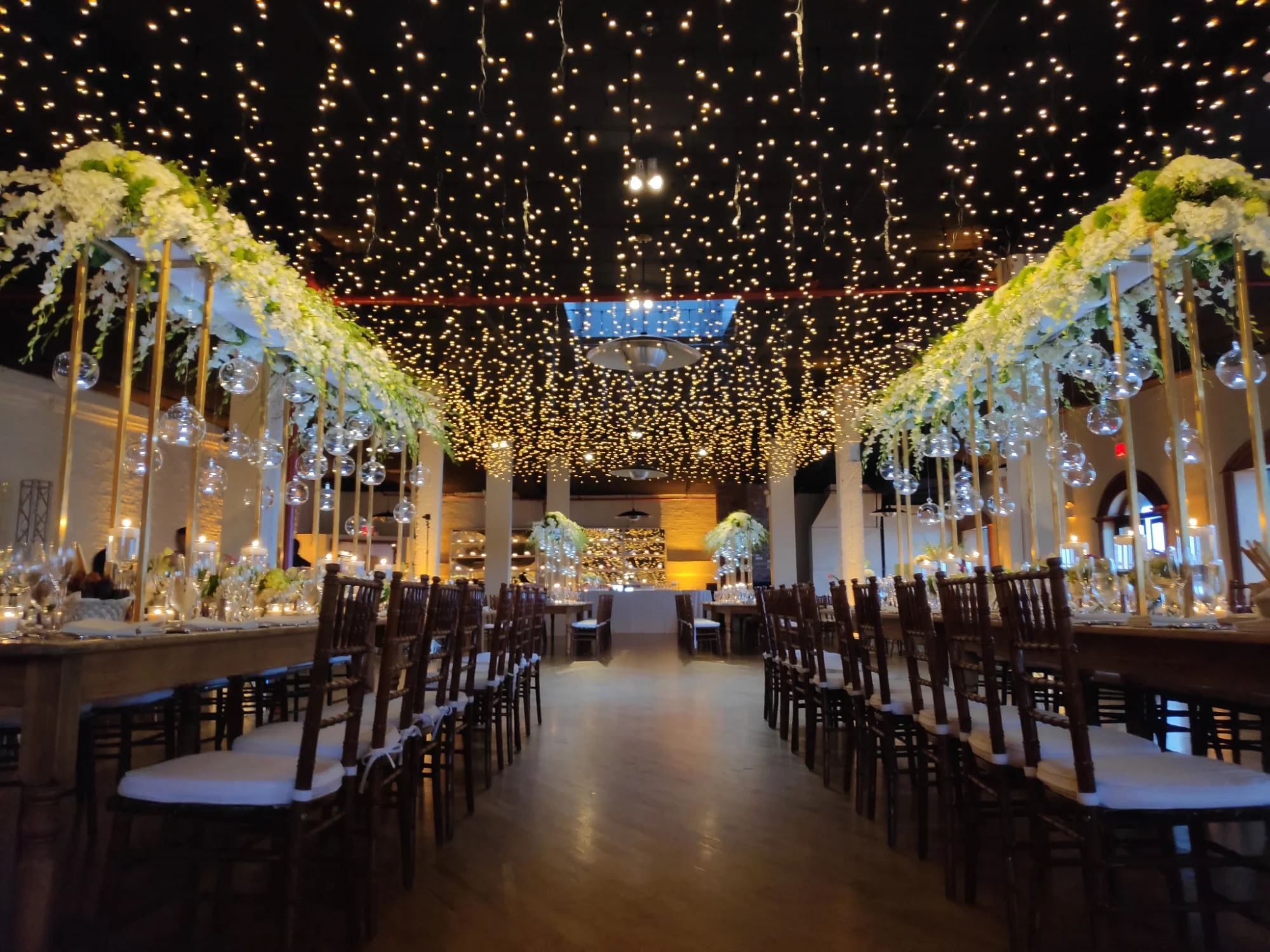 Interior of The Liberty Warehouse in Red Hook with twinkling ceiling lights and long banquet tables.