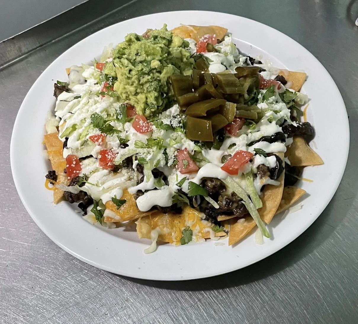Plate of nachos with guacamole, cream, cheese, and jalapenos at DJ & C Reyna Restaurant, Morris Heights.