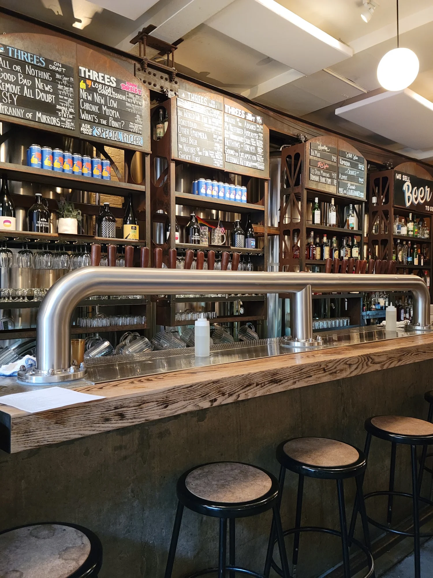 Threes Brewing featured image Interior bar view with stools, taps, and menu boards at Threes Brewing in Gowanus.