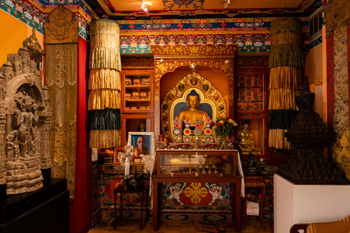 Intricately decorated interior with statues and vibrant textiles at Tibet House US, Flatiron District.