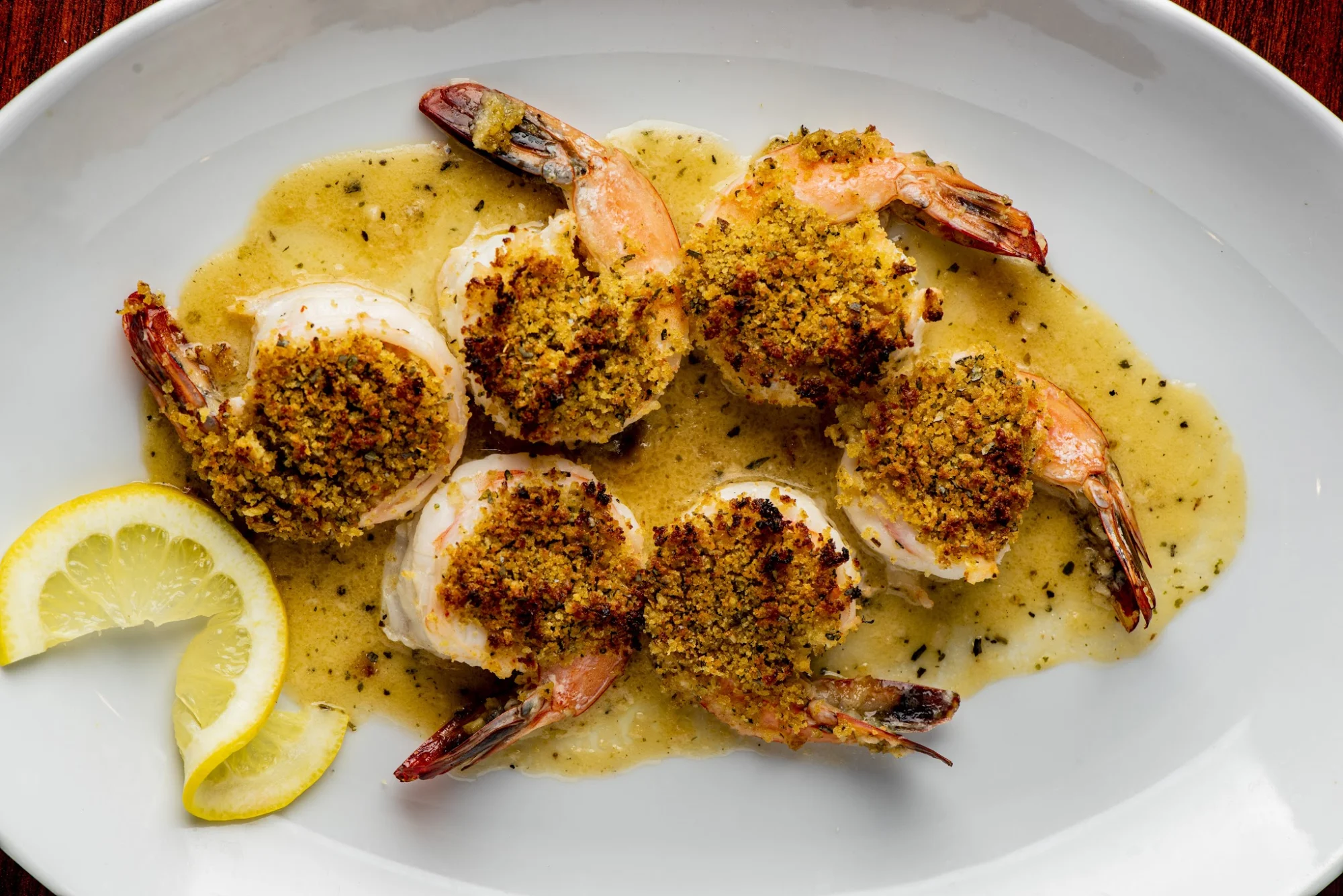 Patrizia's Taverna featured image Baked shrimp with breadcrumb topping and lemon slices on a white plate at Patrizia's Taverna, New Dorp.