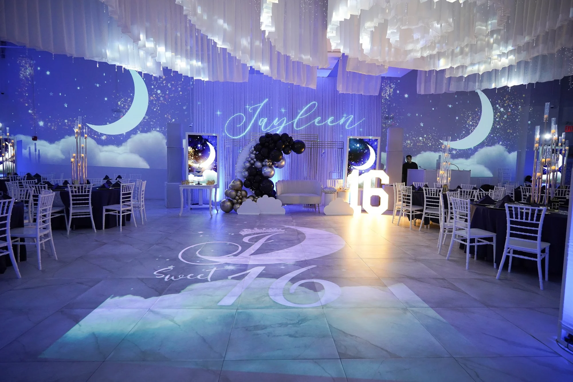 Interior event space with moonlit decor, white chairs and tables, East Elmhurst.